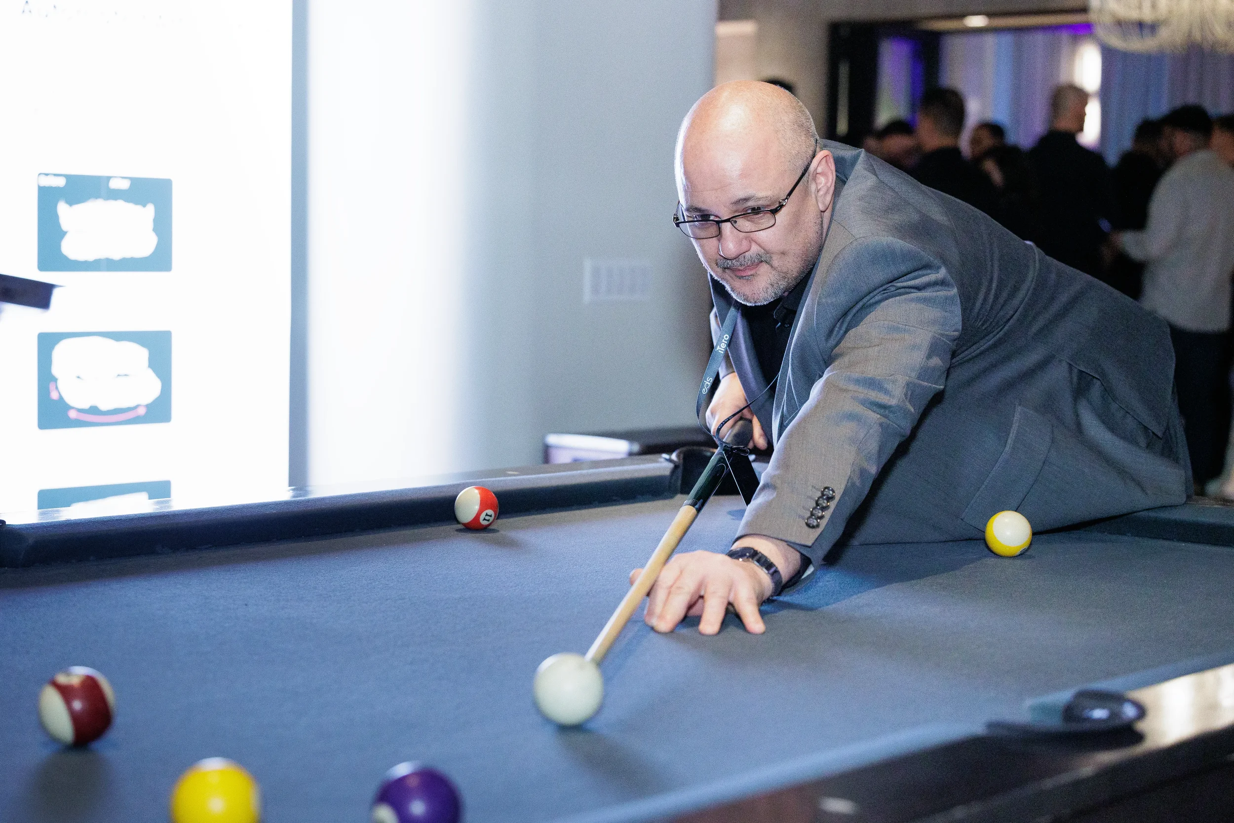 Attendee leans over pool table taking a shot during networking reception at Chicago corporate event