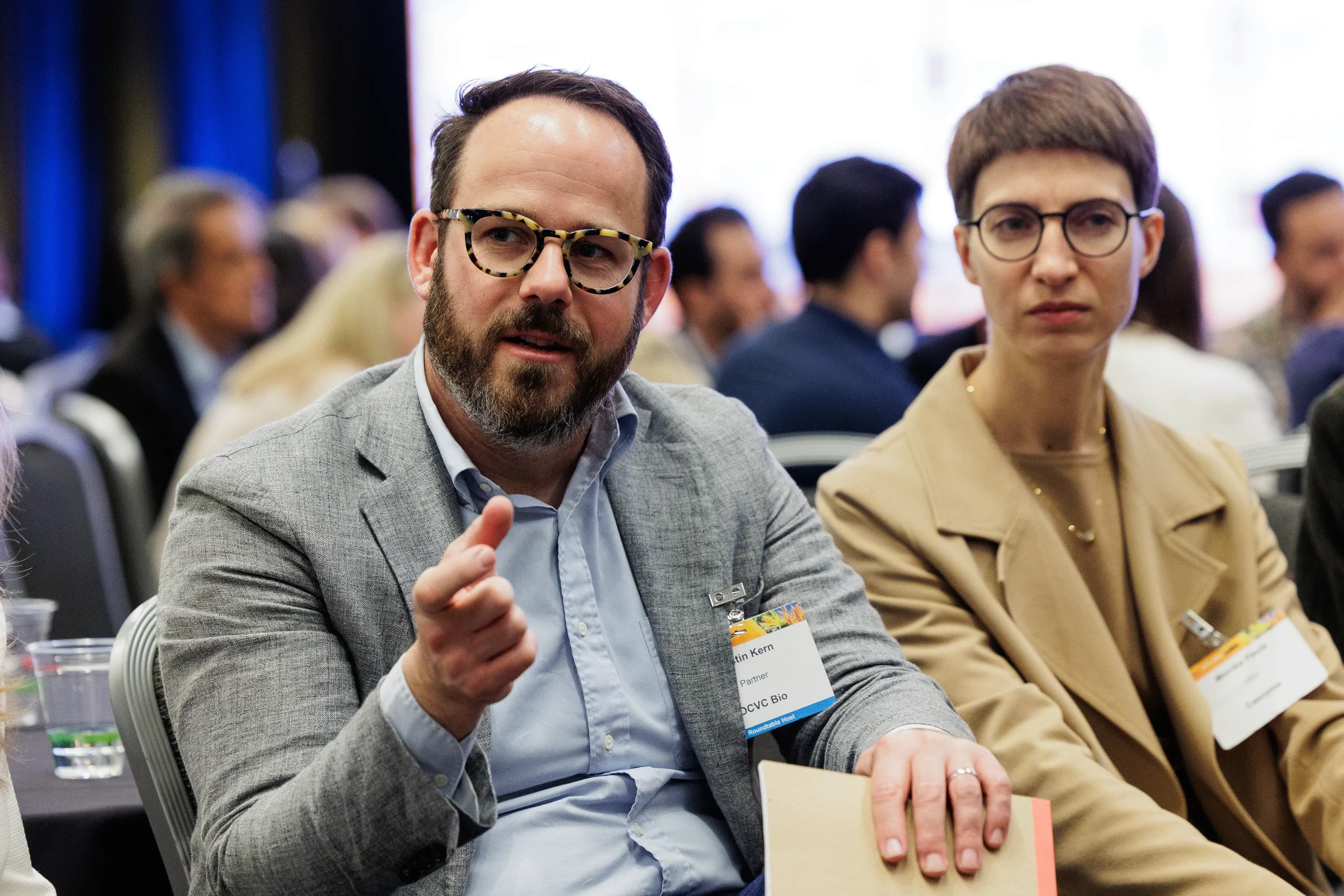 Two badged attendees engage in discussion at roundtable networking session at Orlando corporate conference
