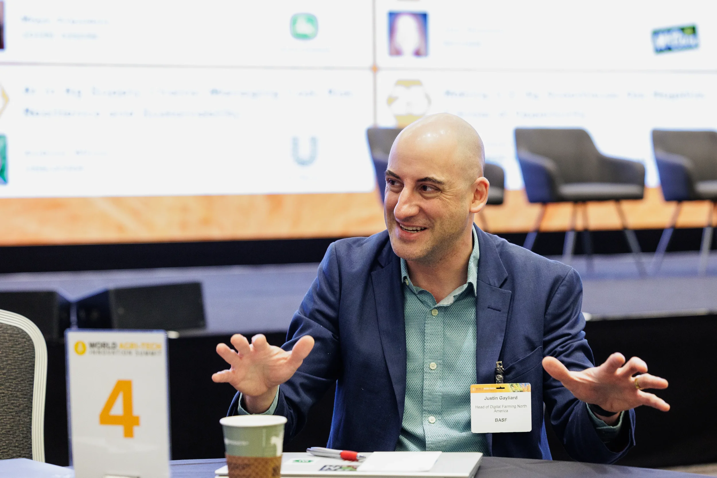 Attendee with name badge gestures expressively during branded roundtable session at Orlando industry conference