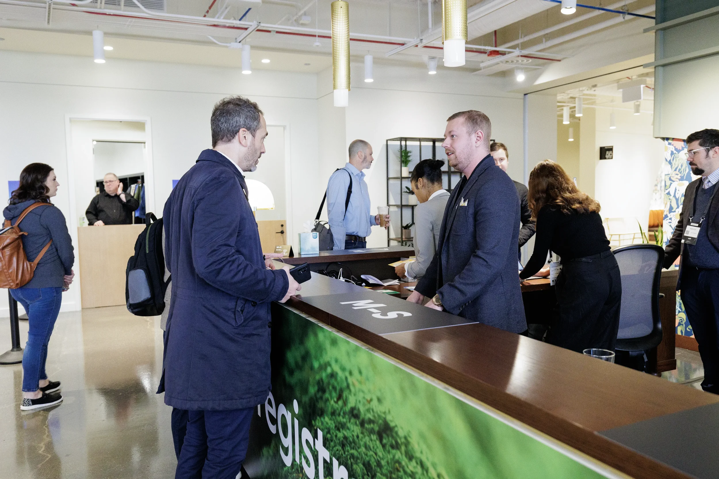 Attendee checks in with staff at registration desk in busy lobby at Chicago corporate conference