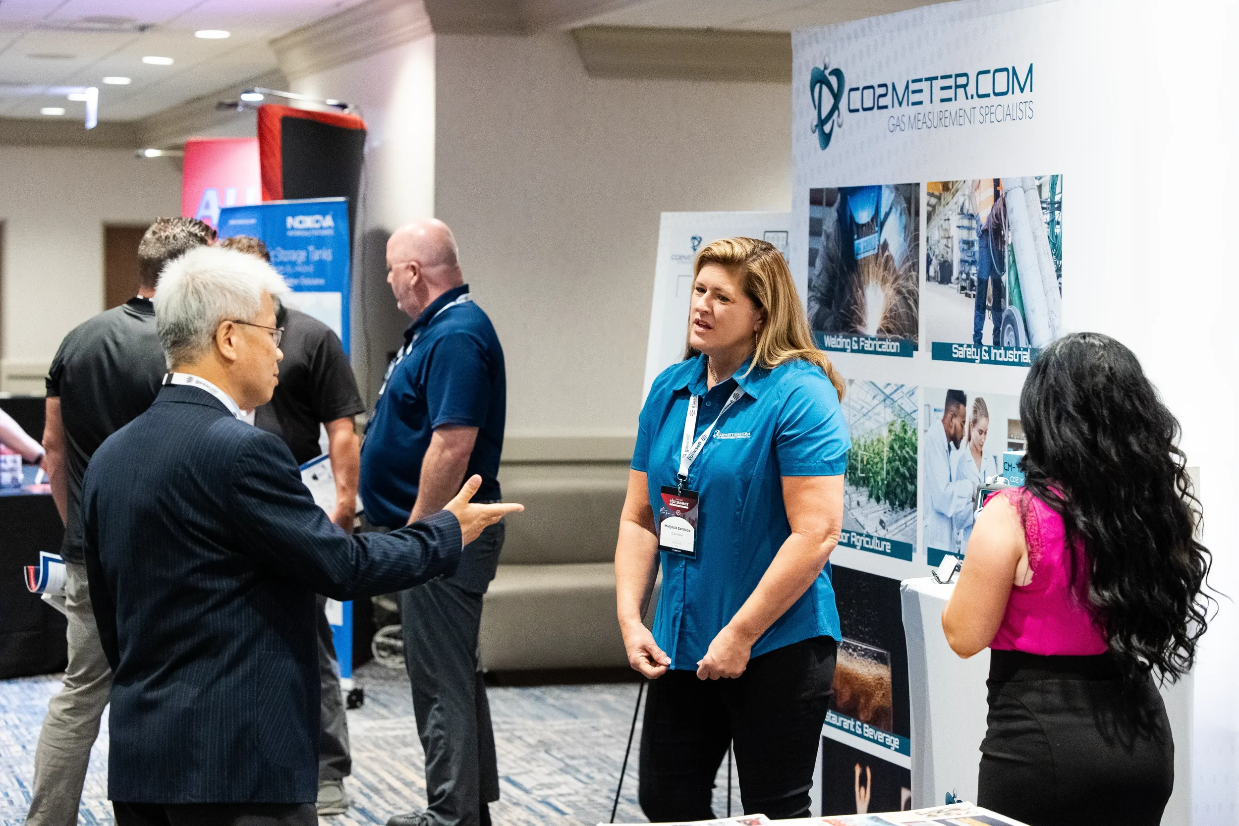 Exhibitor speaks with attendees at trade show booth on Orlando conference expo floor