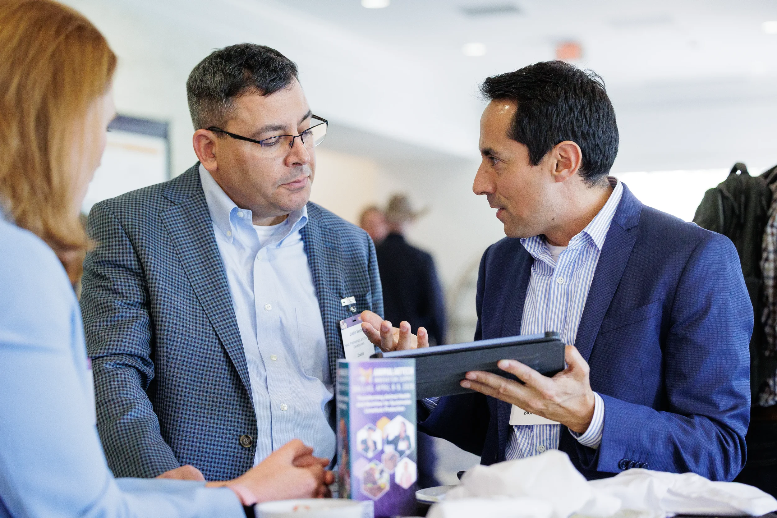 Two attendees discuss content on tablet during conversation at Orlando corporate conference