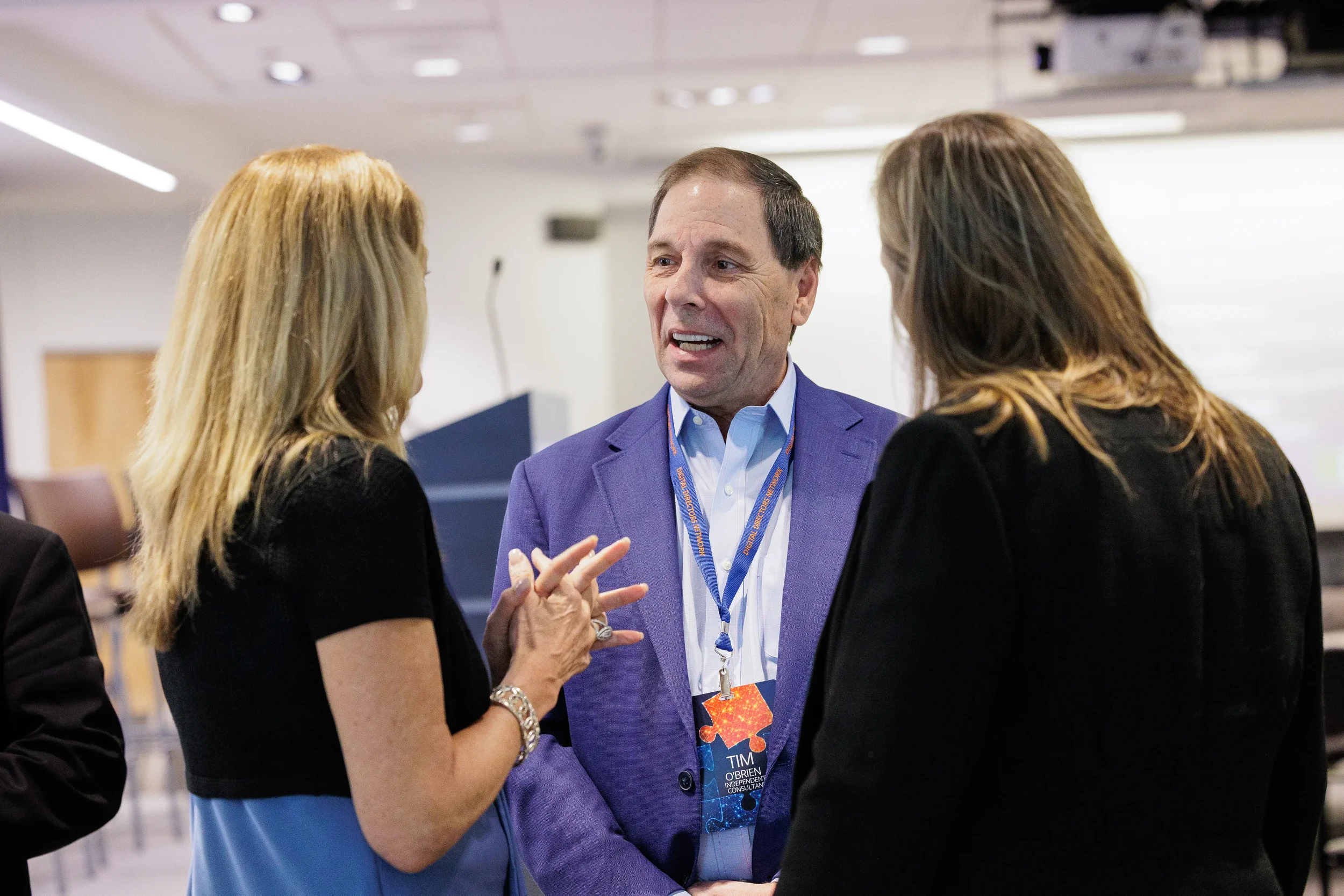Three attendees with lanyards converse during networking break at Chicago corporate conference event