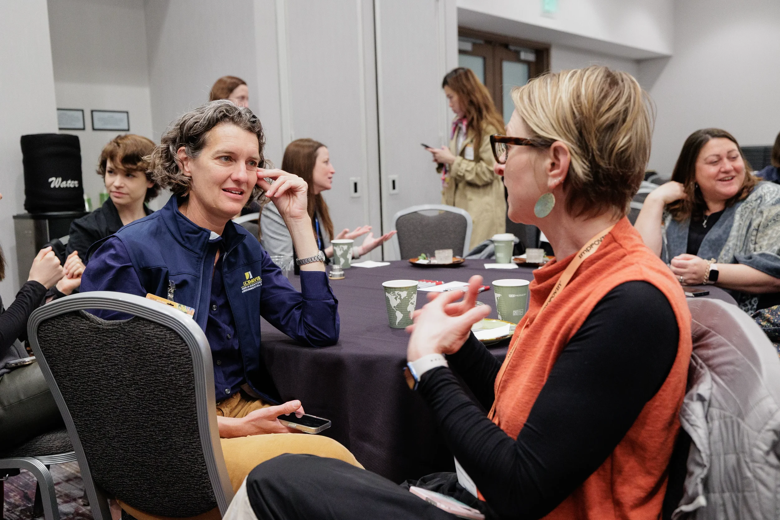 Two badged female attendees in conversation at table during Chicago corporate conference breakfast event