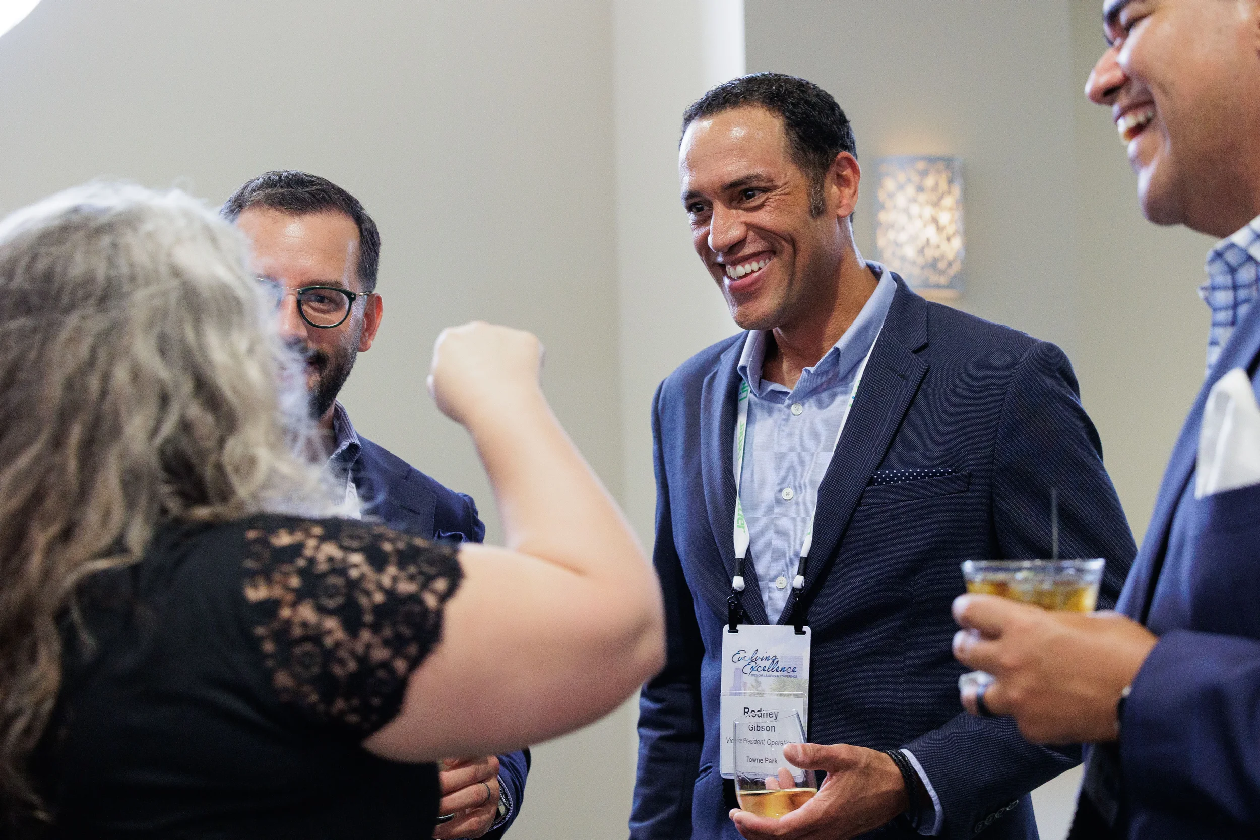 Attendees laugh and share fist bump over drinks during Orlando industry conference networking reception