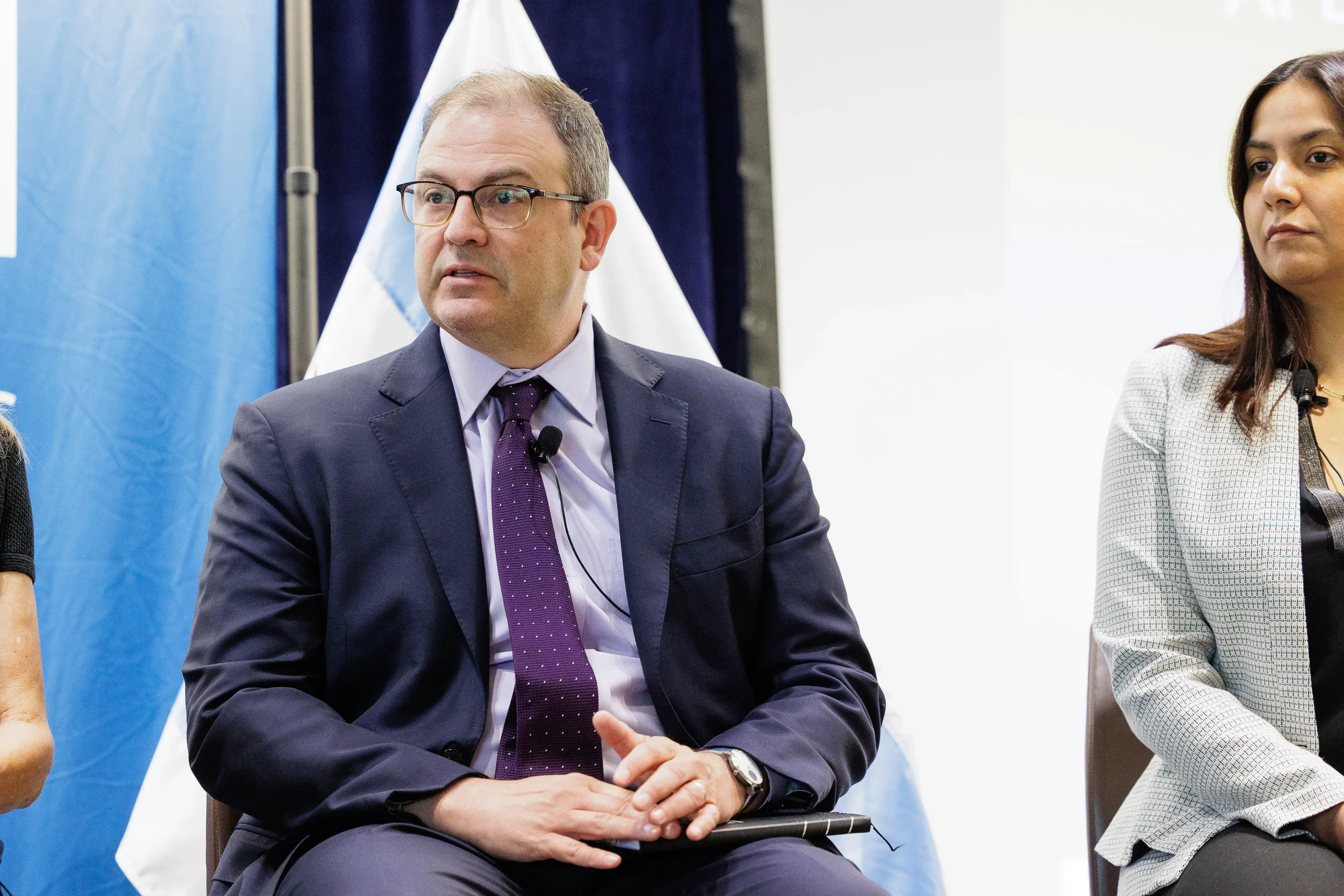 Male panelist seated and speaking beside Chicago flag at Chicago corporate conference panel discussion