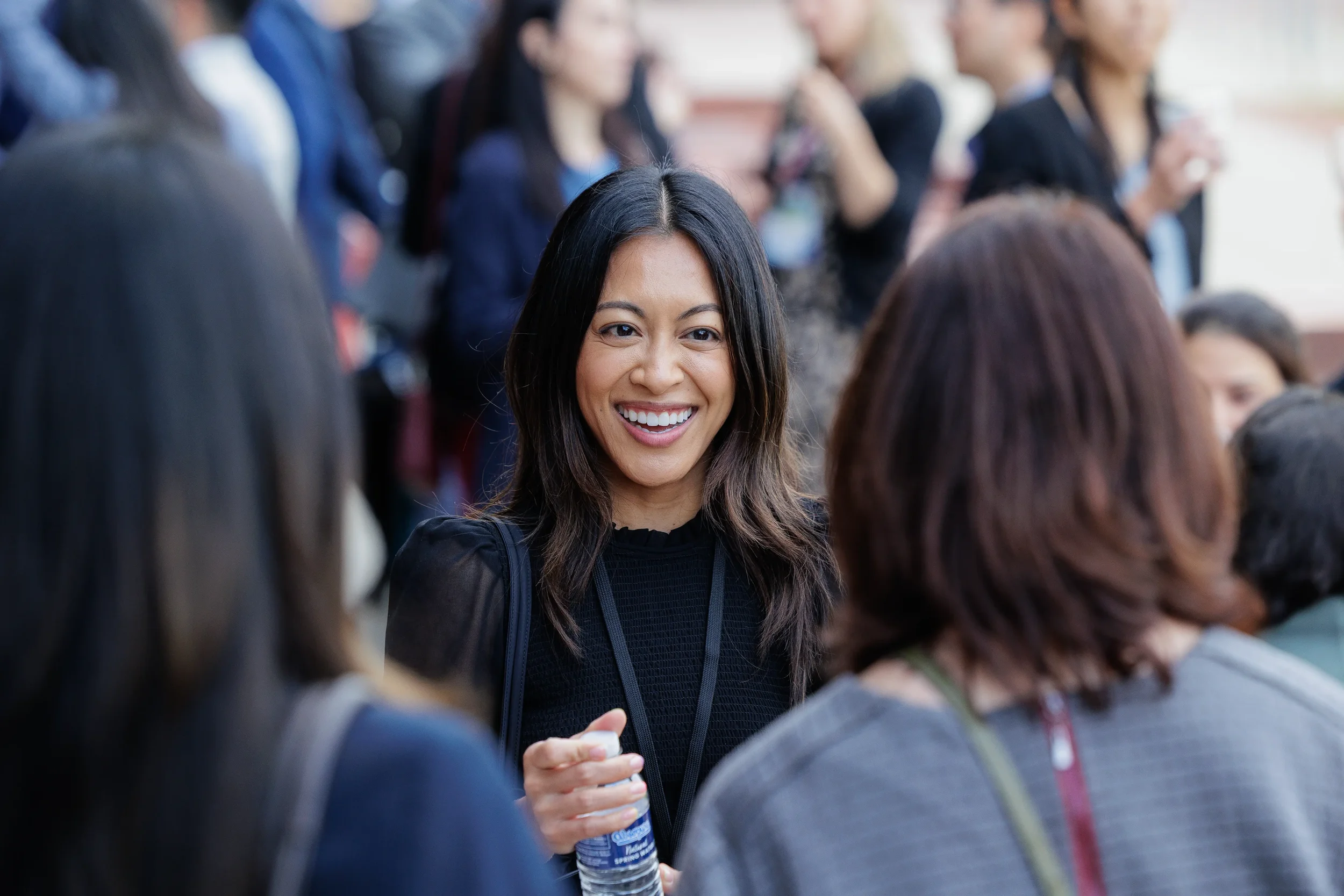 Smiling attendee holds water bottle while networking in crowded Chicago corporate reception