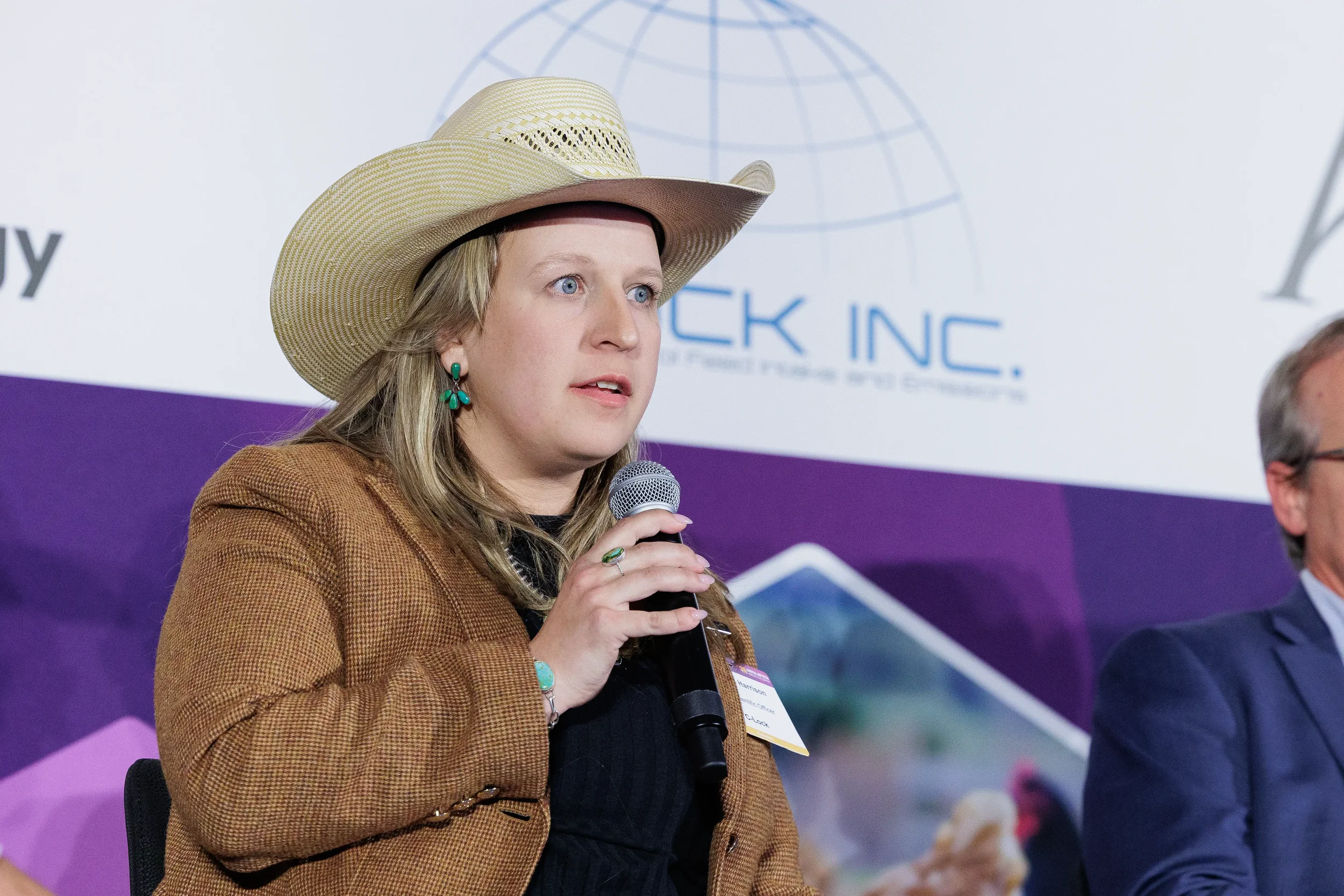 Panelist wearing cowboy hat speaks into microphone during seated discussion at Orlando summit