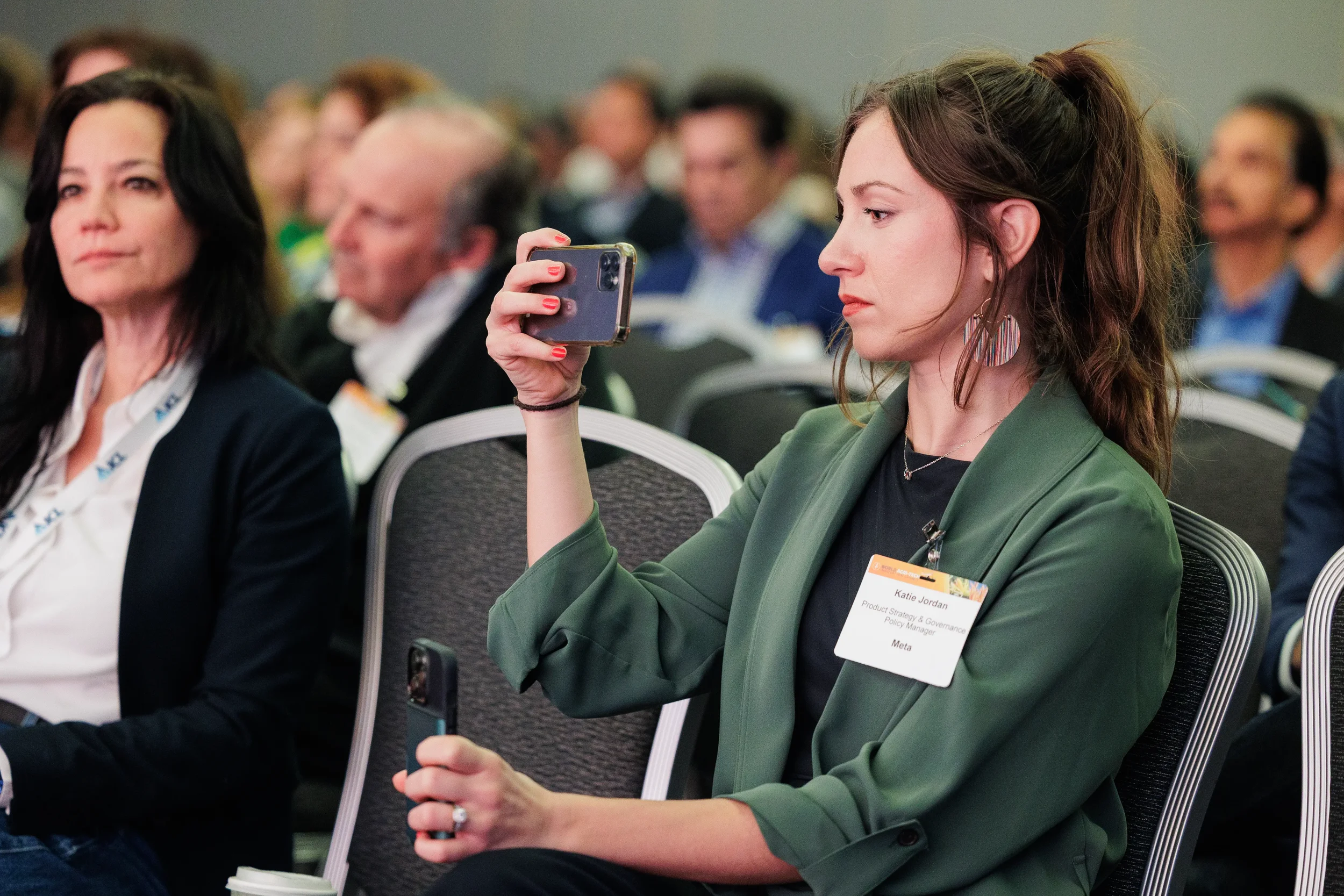 Badged attendee holds up phone to photograph presentation during session at Orlando corporate conference