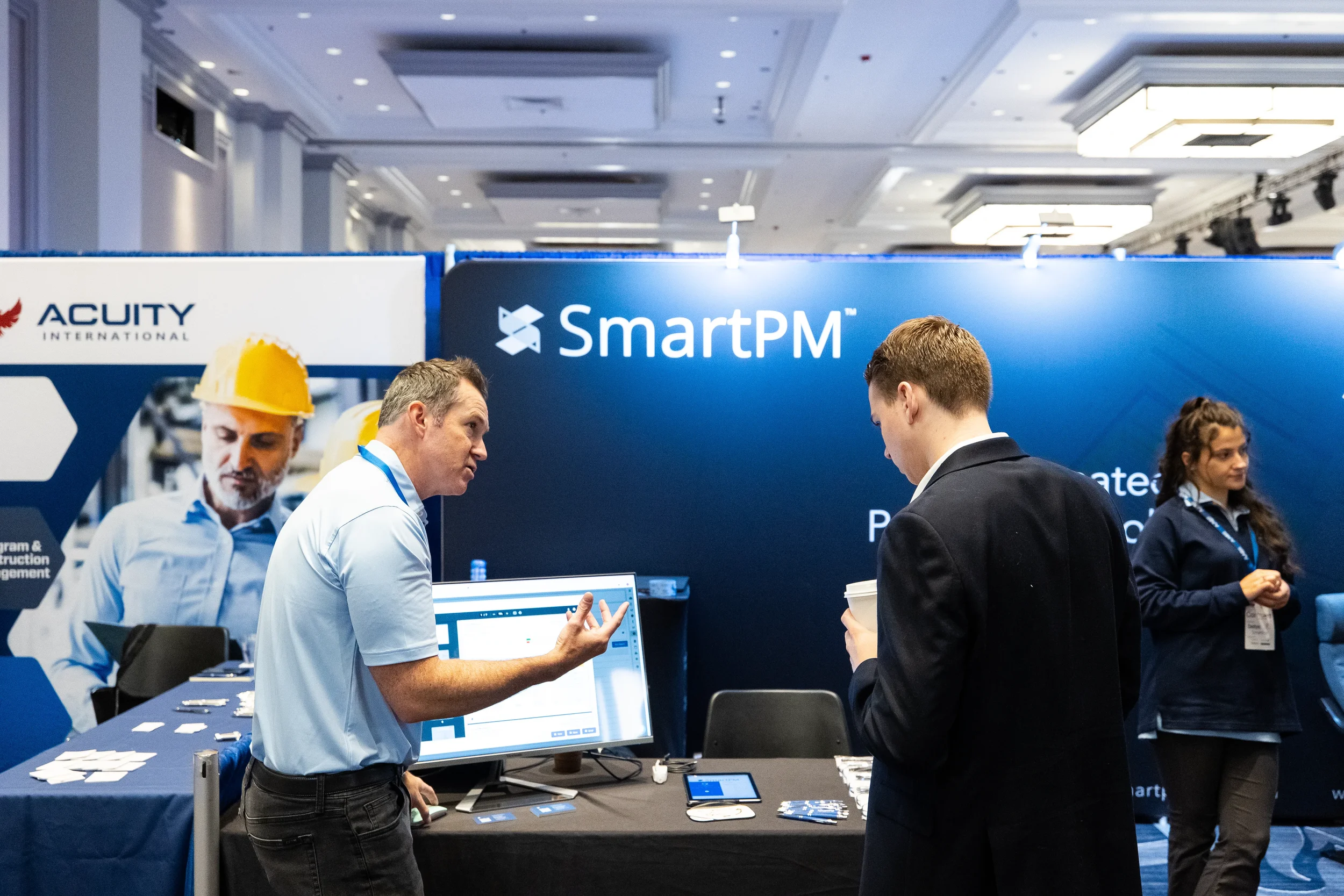 Exhibitor demonstrates software to attendee at trade show booth during Orlando conference