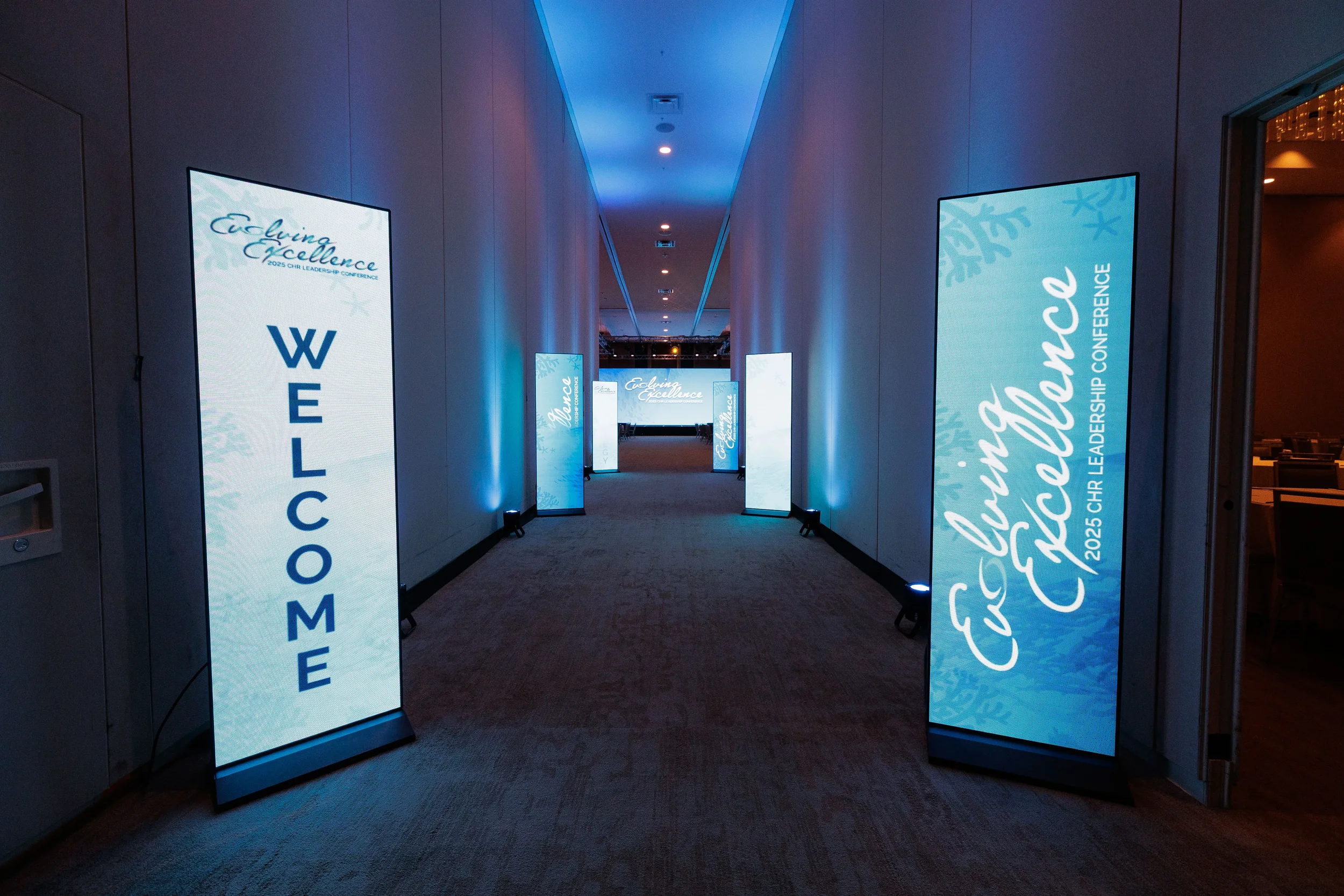Illuminated branded welcome corridor with LED display panels leading into Orlando corporate conference venue