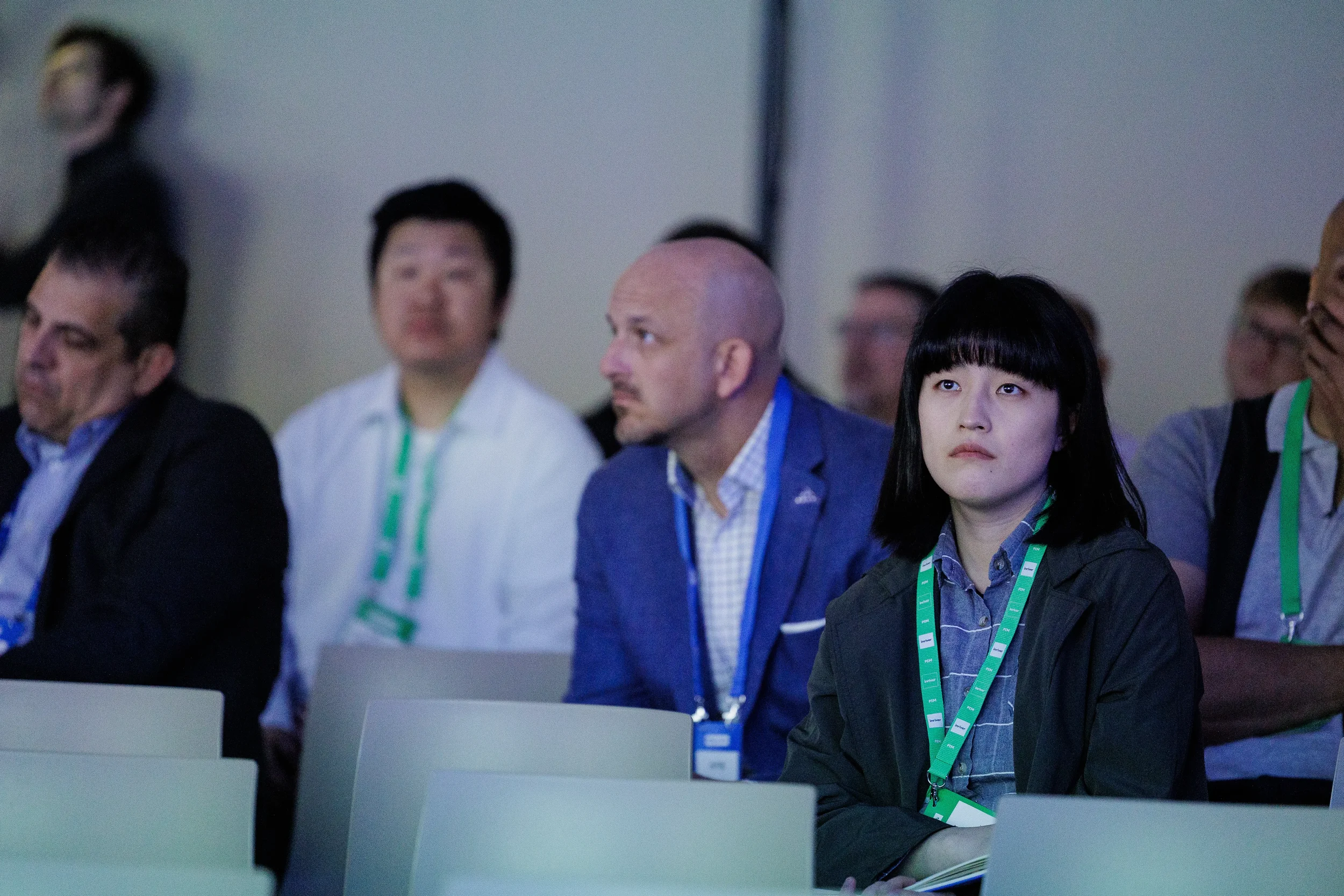 Attentive attendees with green lanyards watch session from seated rows at Orlando corporate conference