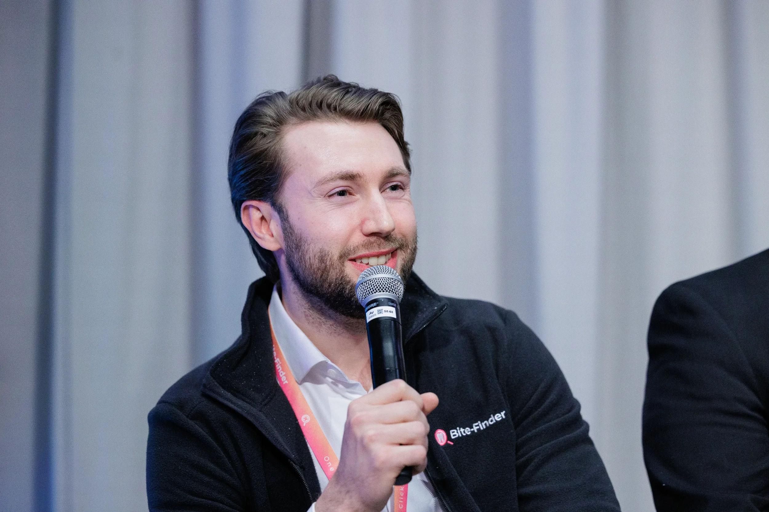 Smiling panelist speaks into microphone in close-up shot at Orlando industry conference