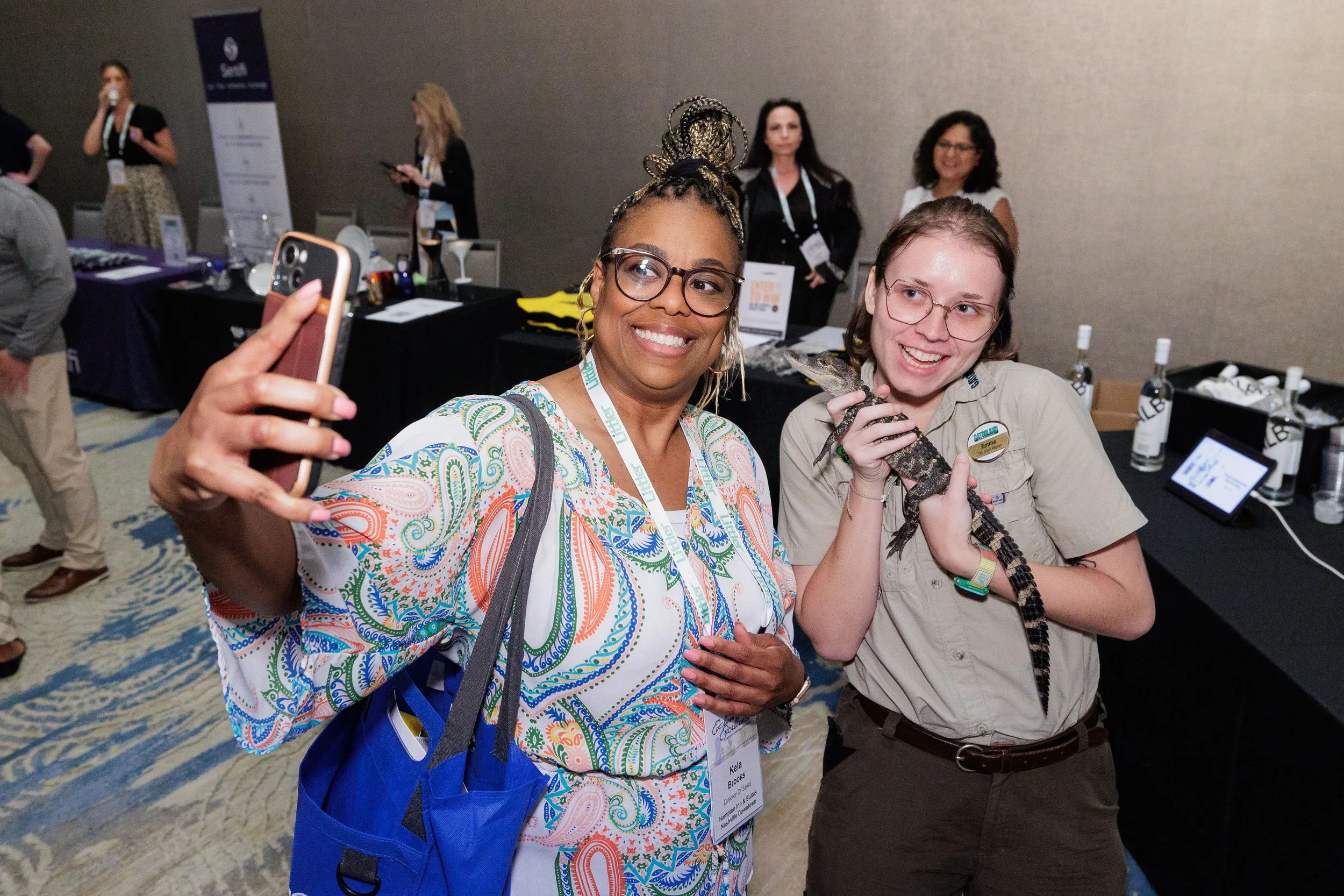 Attendee takes selfie with wildlife handler holding alligator at Chicago industry conference expo floor