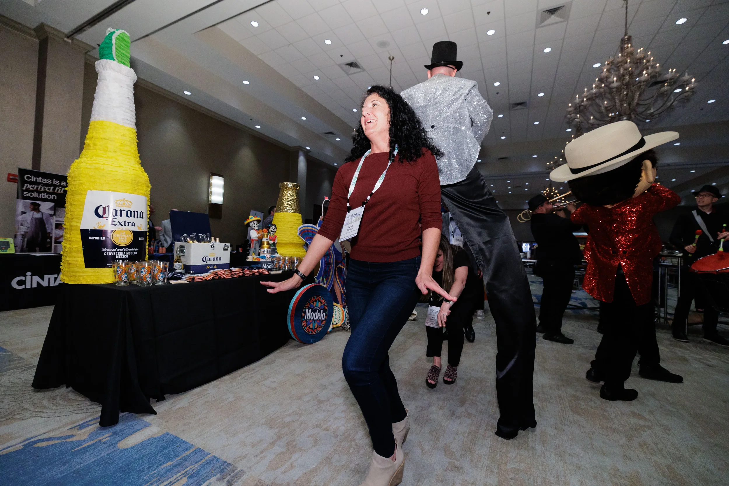 Female attendee dances with costumed stilt entertainer and mascot at Orlando corporate conference gala