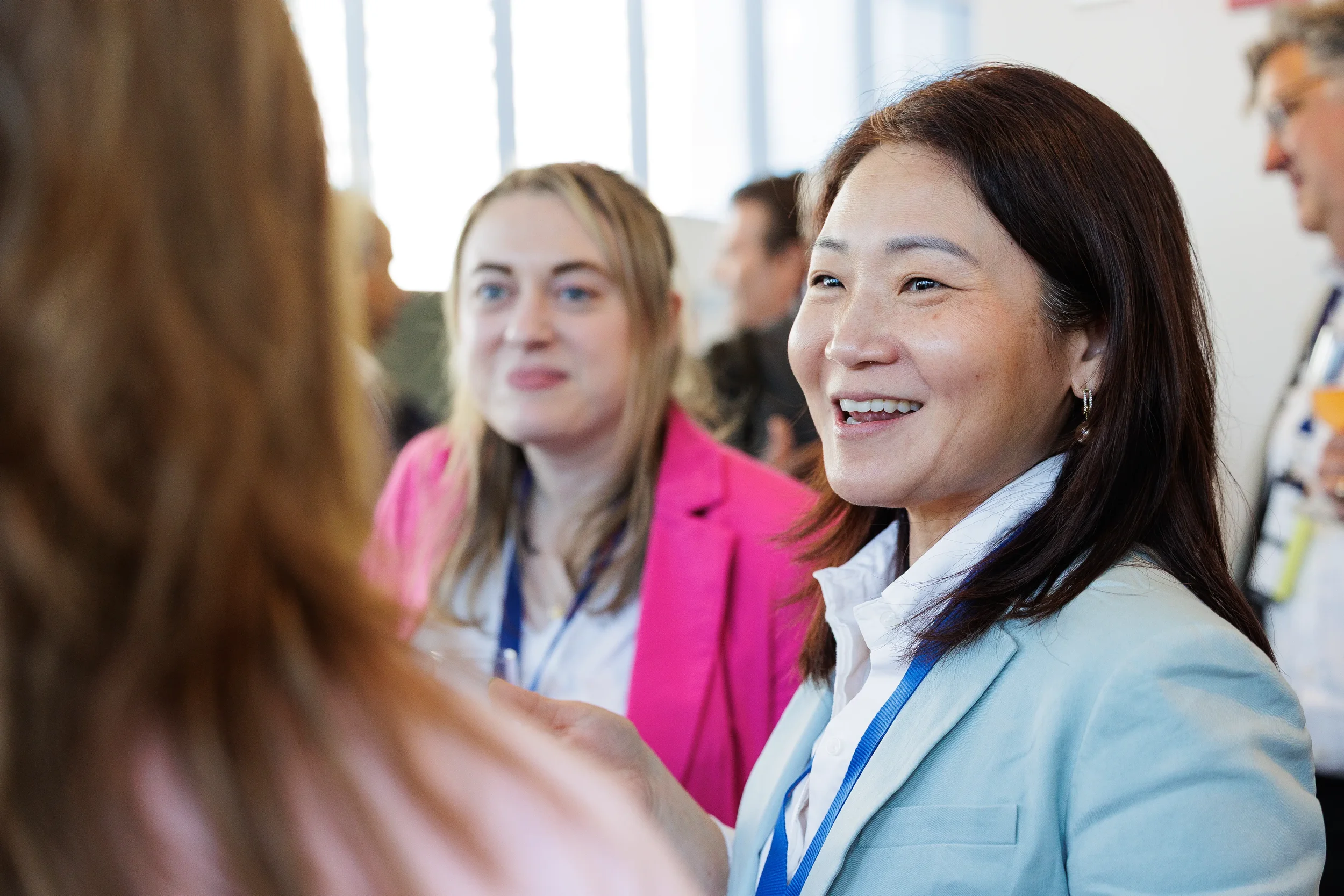 Female attendees with lanyards smile and converse during networking reception at Orlando corporate conference