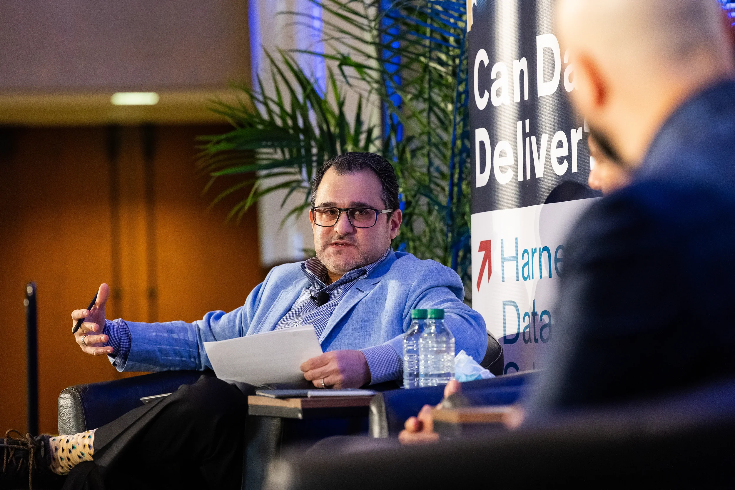 Panelist speaks while holding papers during panel discussion at Orlando corporate conference
