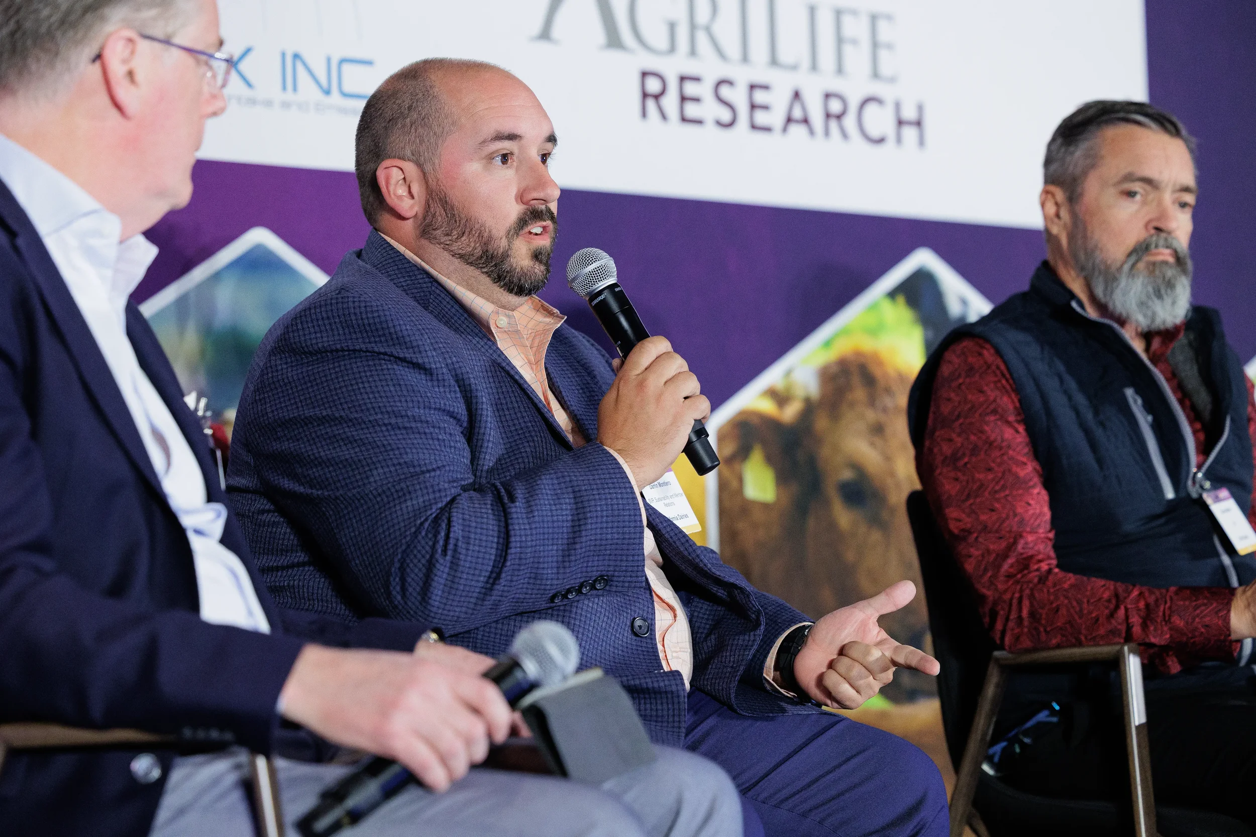 Panelist points while speaking into microphone during seated panel at Chicago industry conference