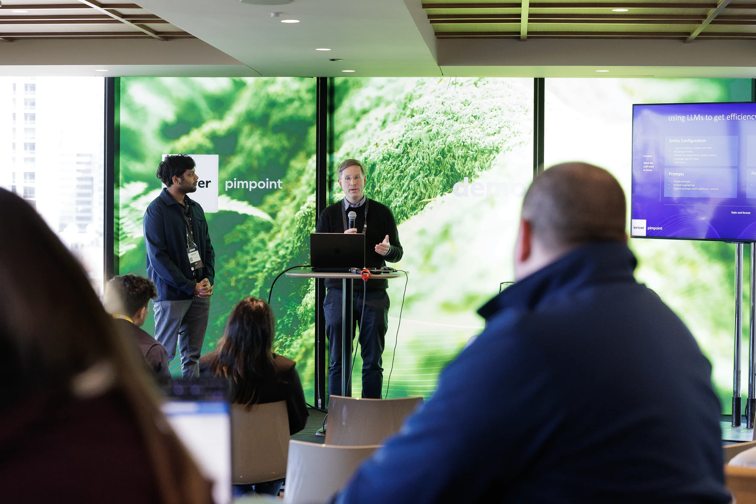 Two presenters give demo with laptop and microphone to audience at Chicago corporate conference