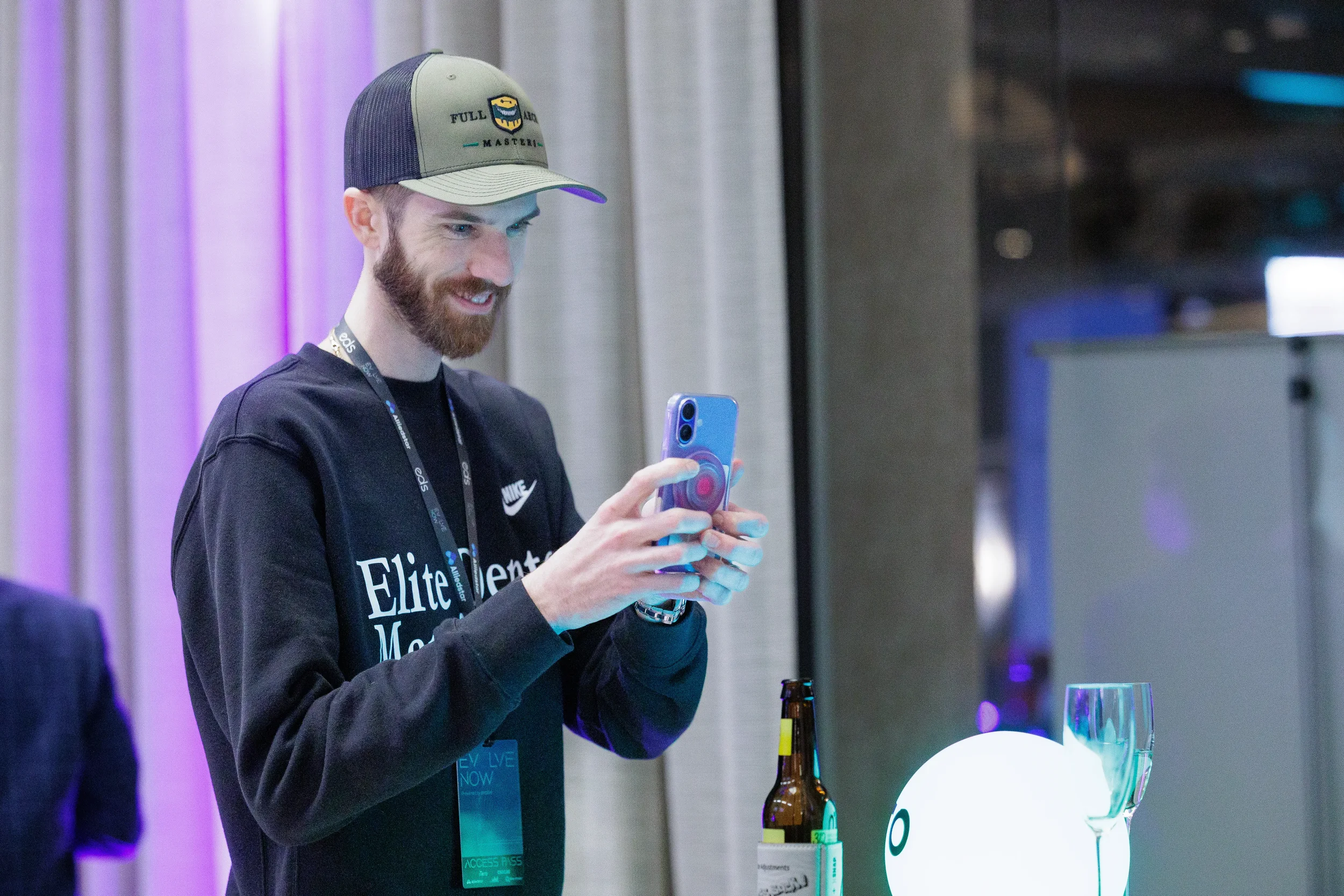 Attendee smiles while photographing with phone at cocktail table during Orlando corporate event