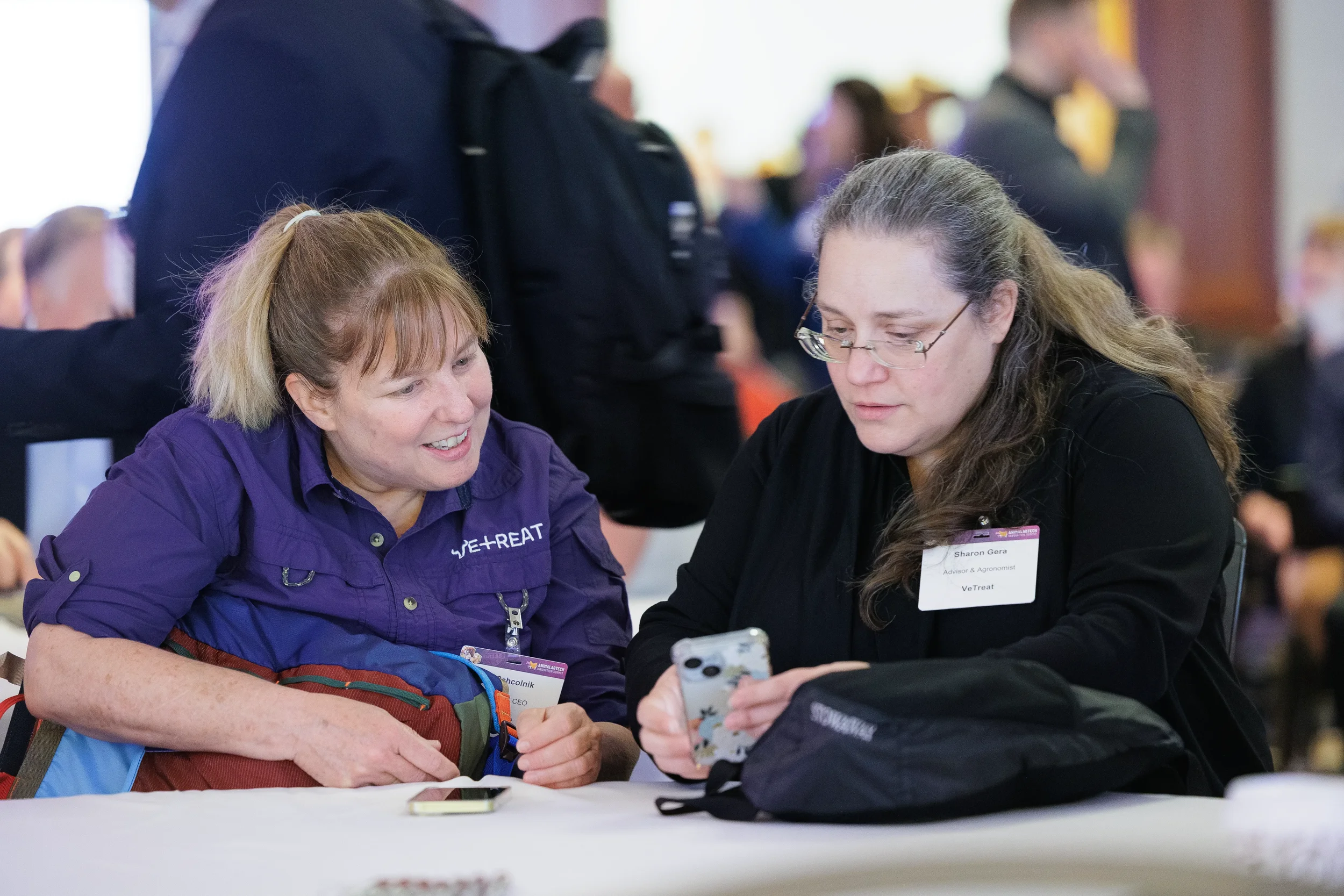 Two attendees look at phone during conversation at seated table at Orlando conference
