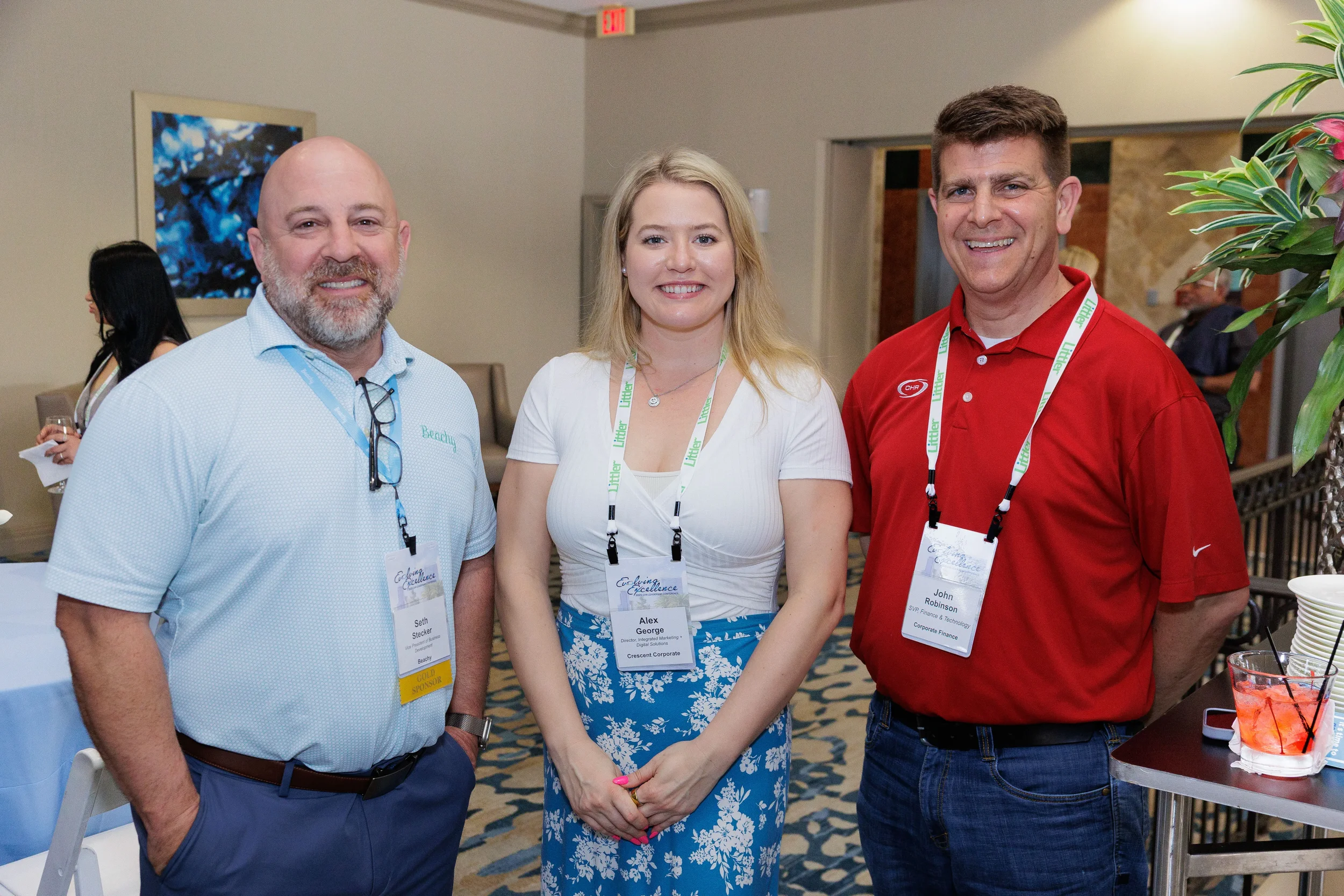 Three attendees with lanyards smile and pose together at Chicago corporate conference networking reception