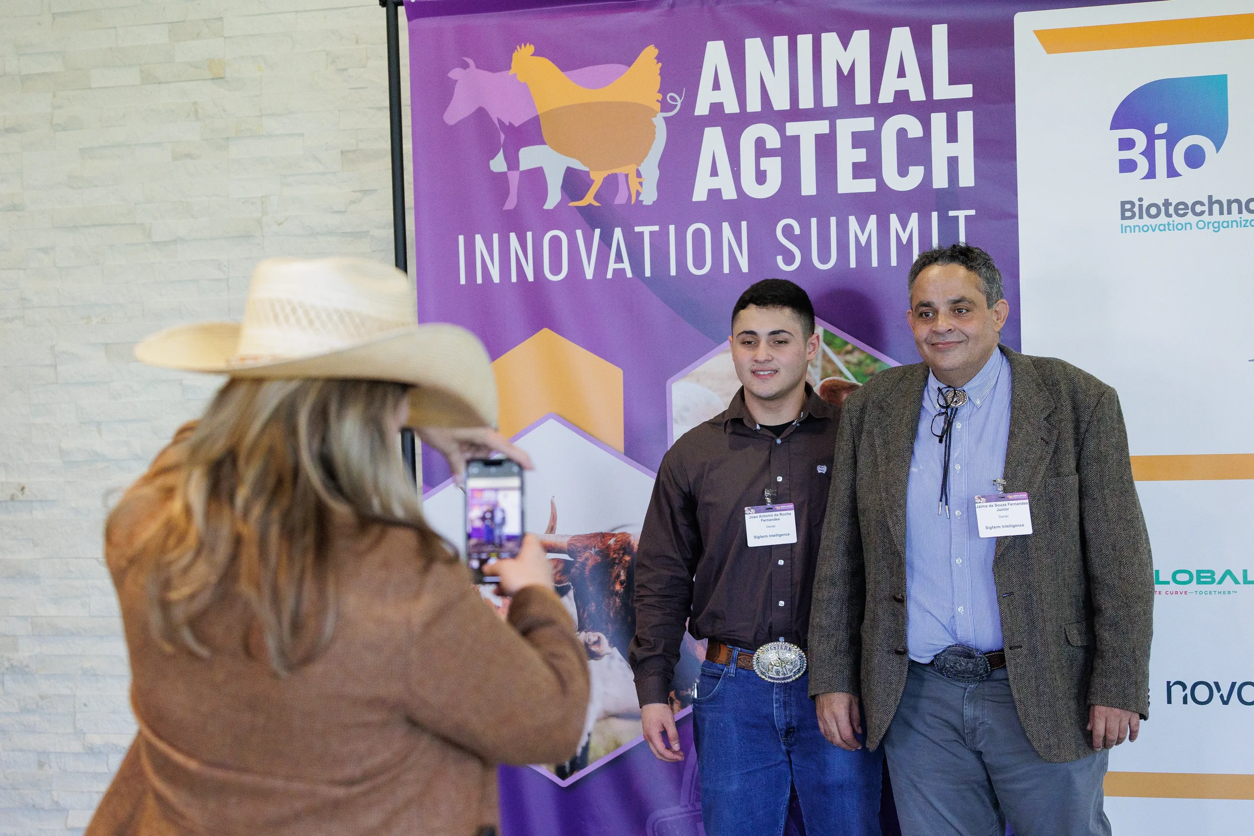 Two attendees pose for a photo in front of event banner at Chicago industry summit