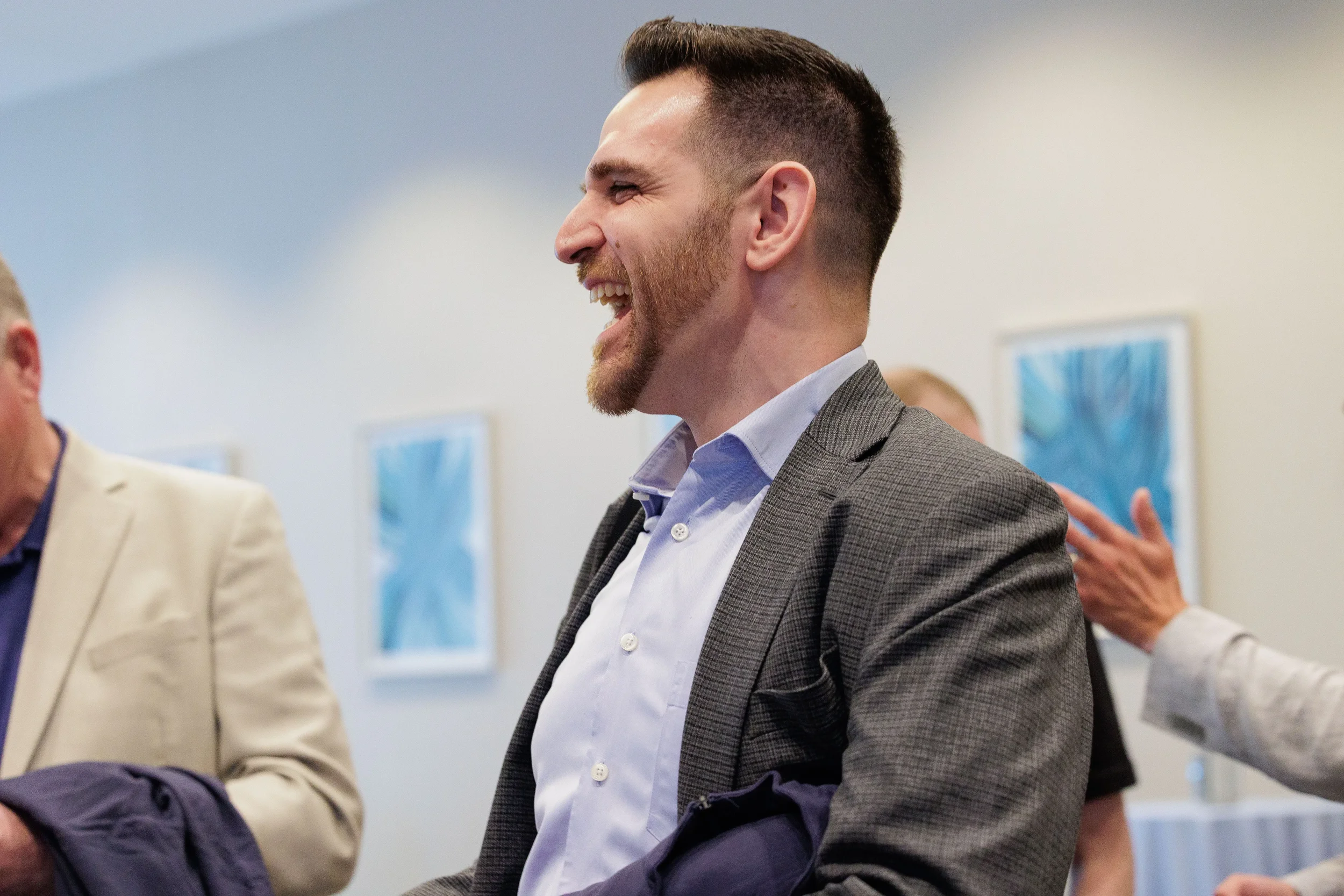 Attendee in blazer laughs candidly during networking reception at Chicago corporate conference