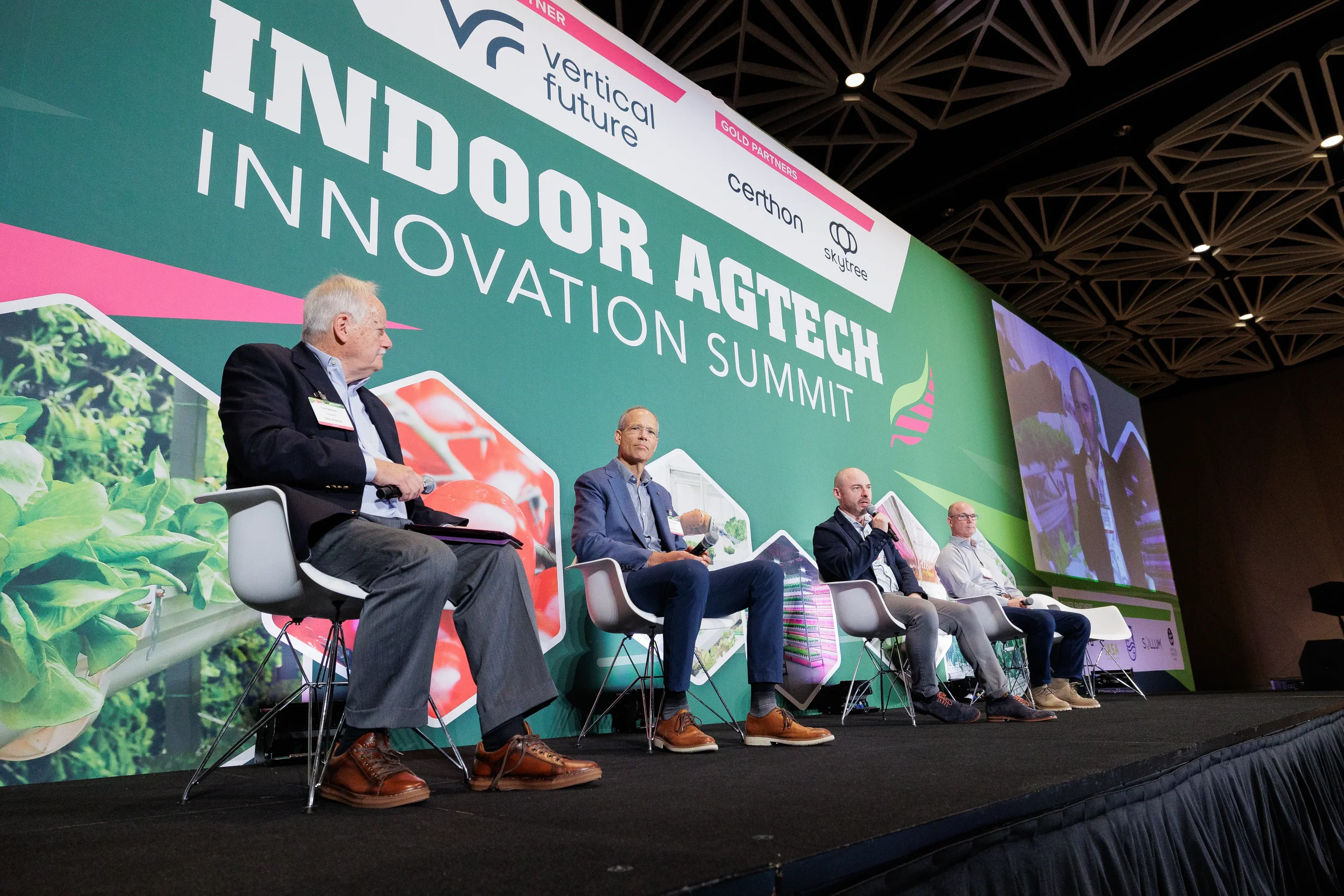 Four panelists seated on stage in front of large branded backdrop at Orlando industry conference