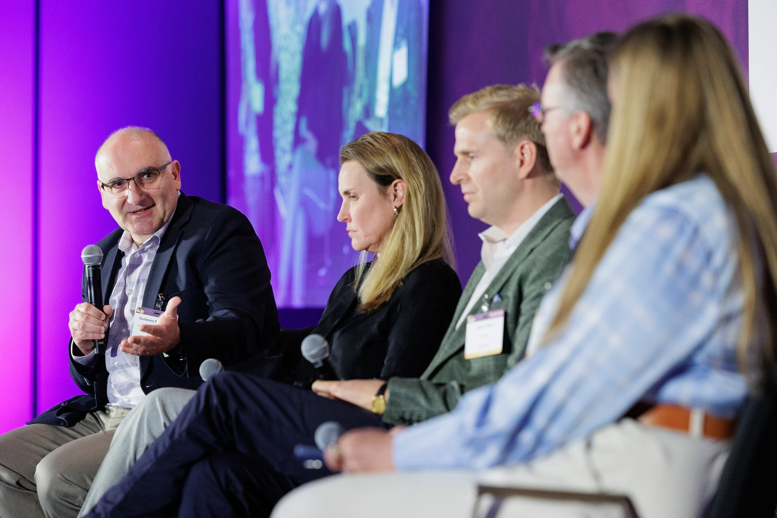 Panelist speaks into microphone during five-person panel discussion at Chicago industry summit