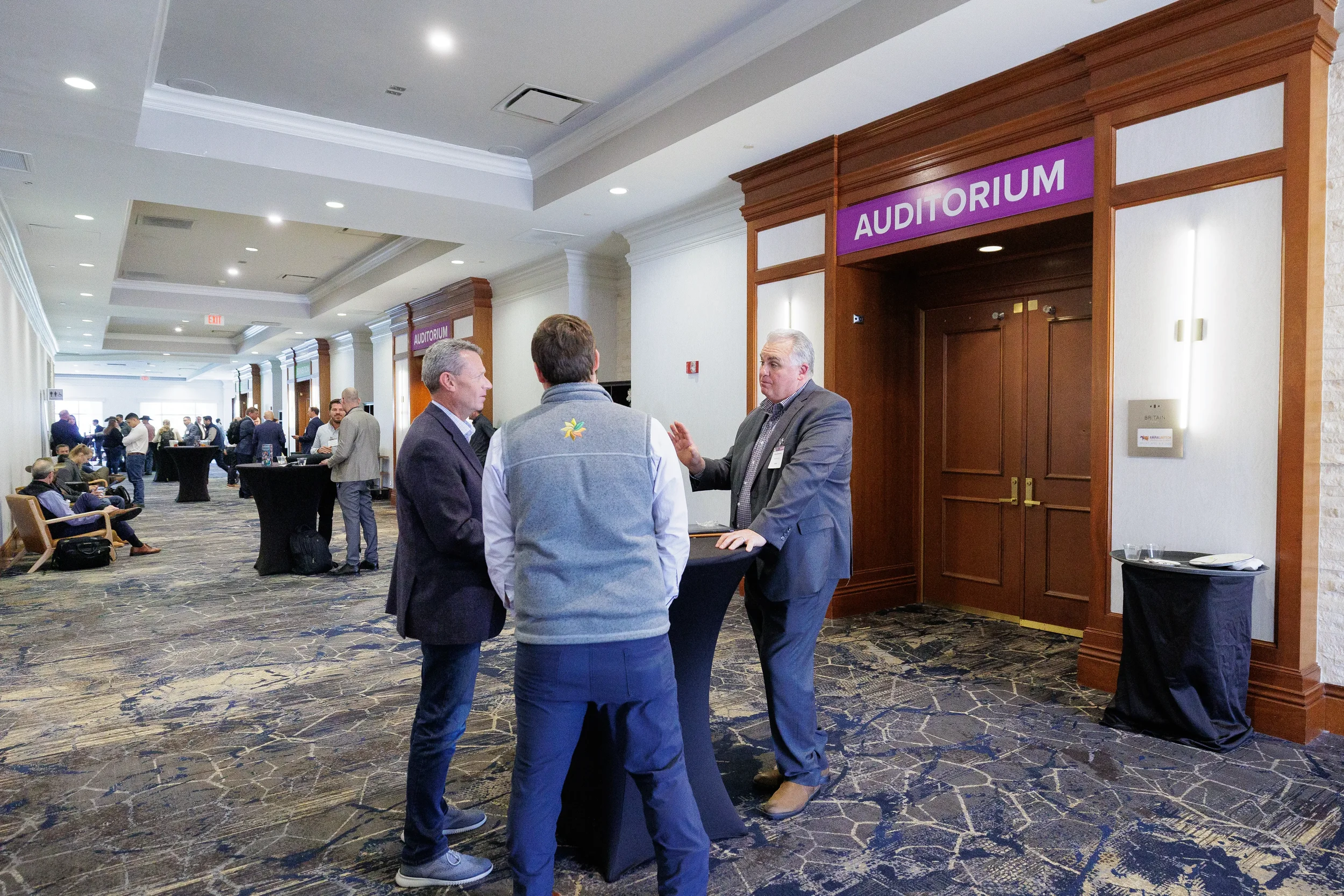Attendees converse in hallway near auditorium entrance at Chicago industry conference