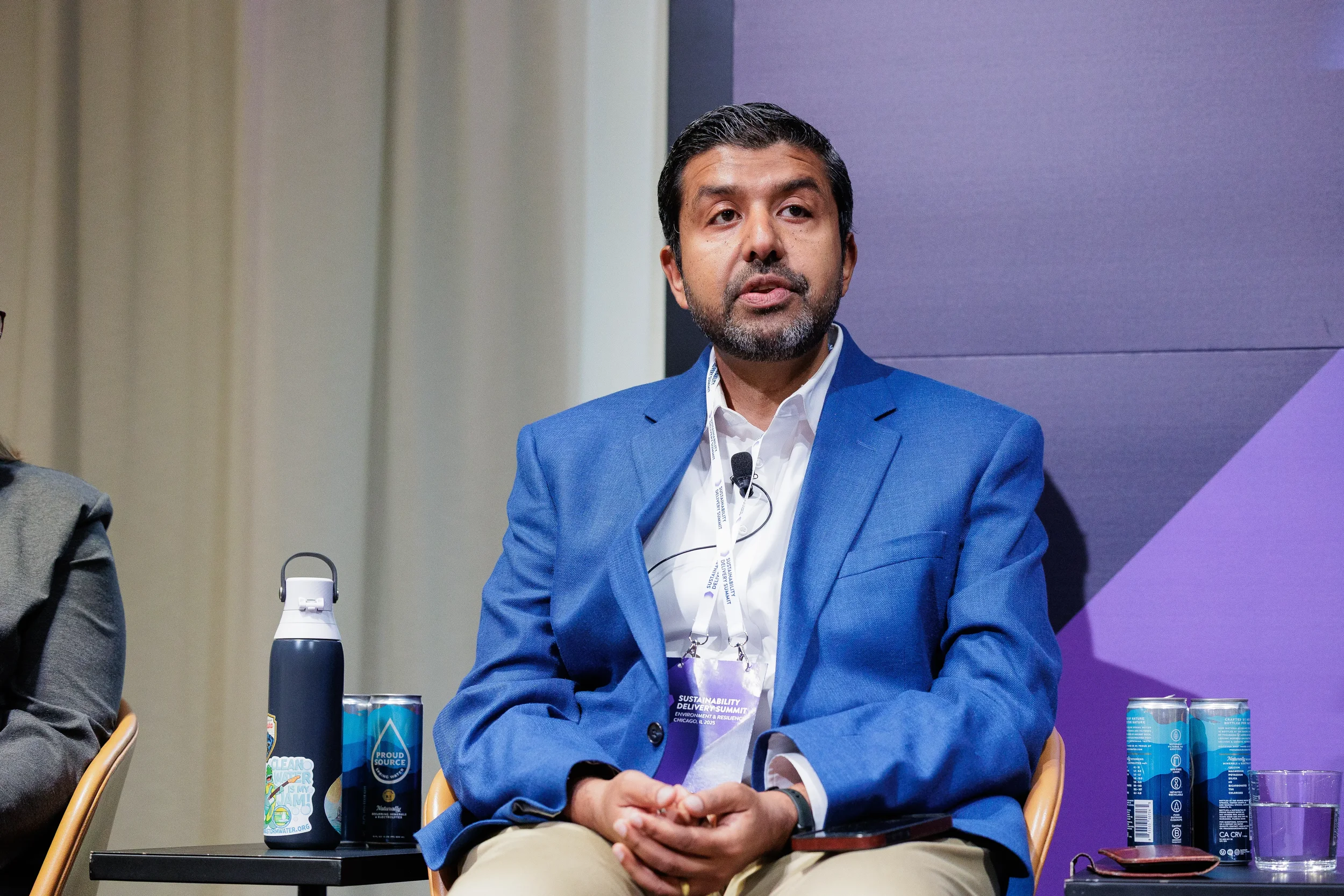 Panelist speaks during seated discussion in front of branded backdrop at Chicago industry summit