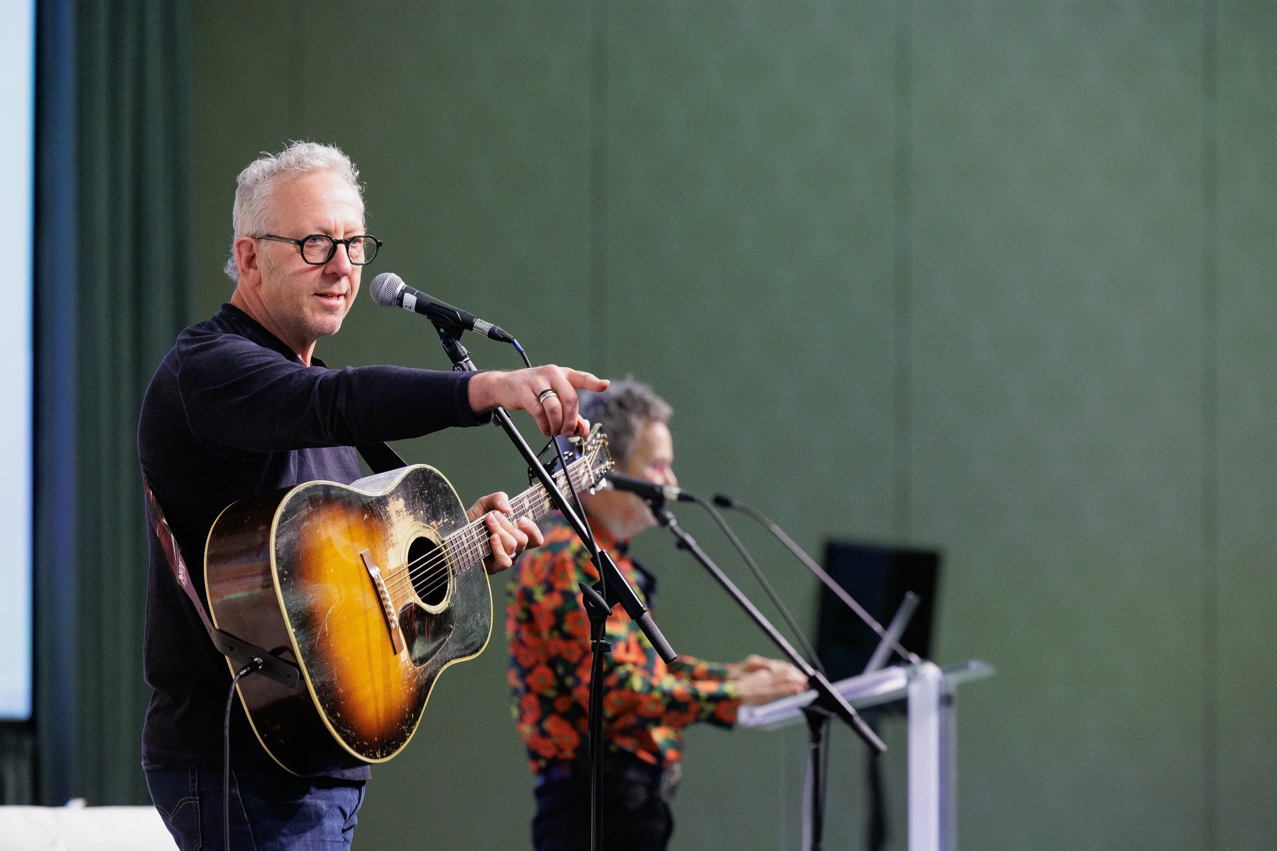 Musician plays guitar and sings into microphone during live performance at Orlando corporate conference