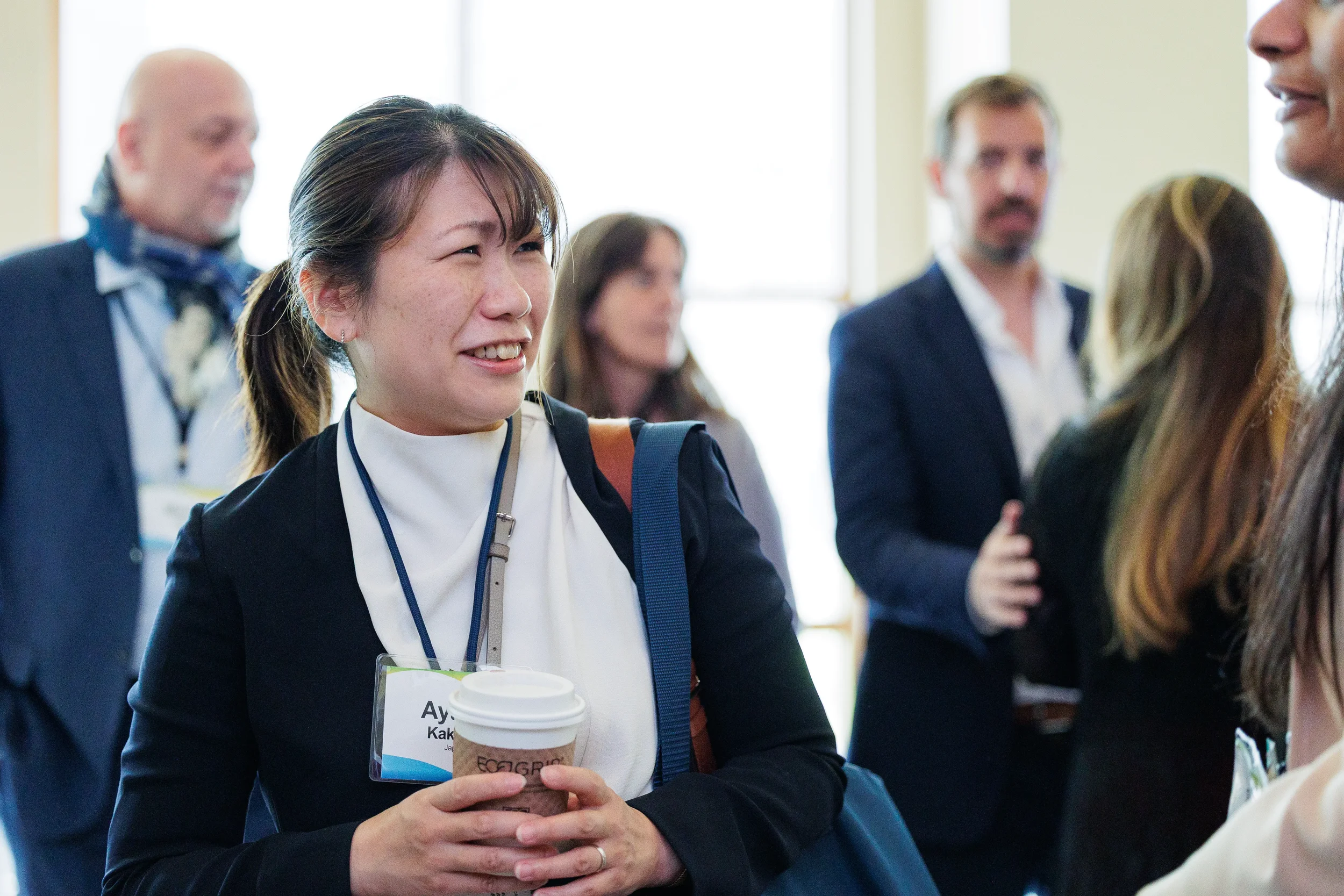 Smiling attendee holds coffee cup while networking with colleagues at Chicago industry conference