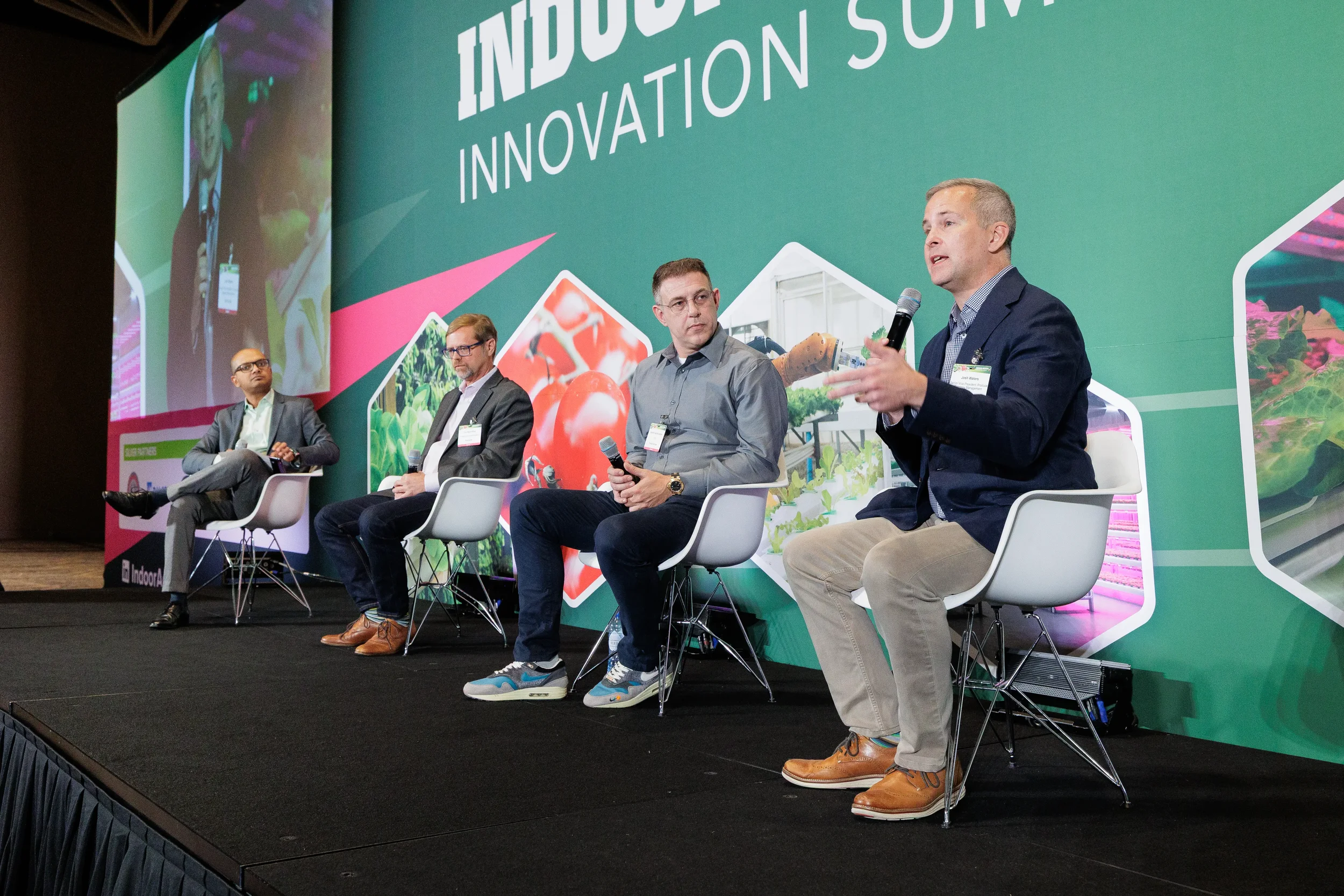 Panelist speaks into microphone while fellow speakers listen on stage at Orlando industry conference