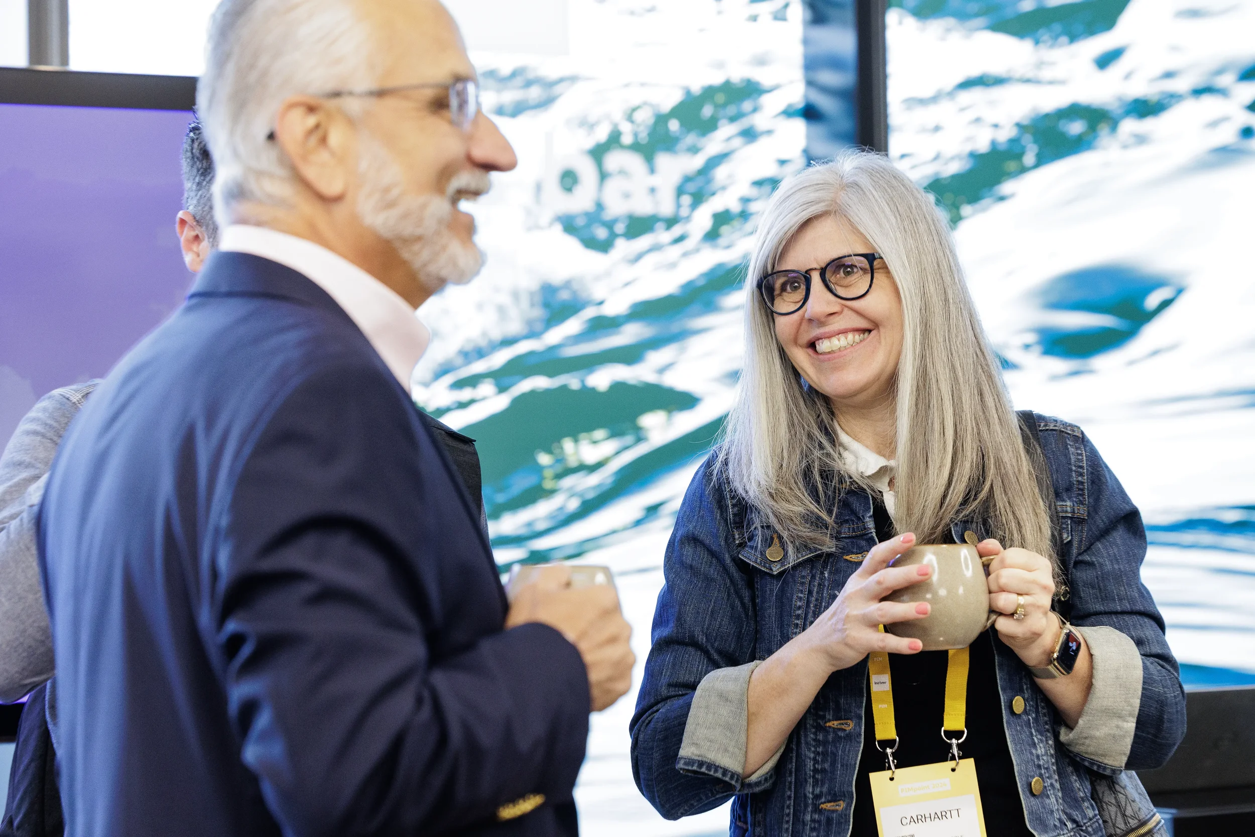Smiling attendee holds coffee mug while networking with colleague at Chicago industry conference