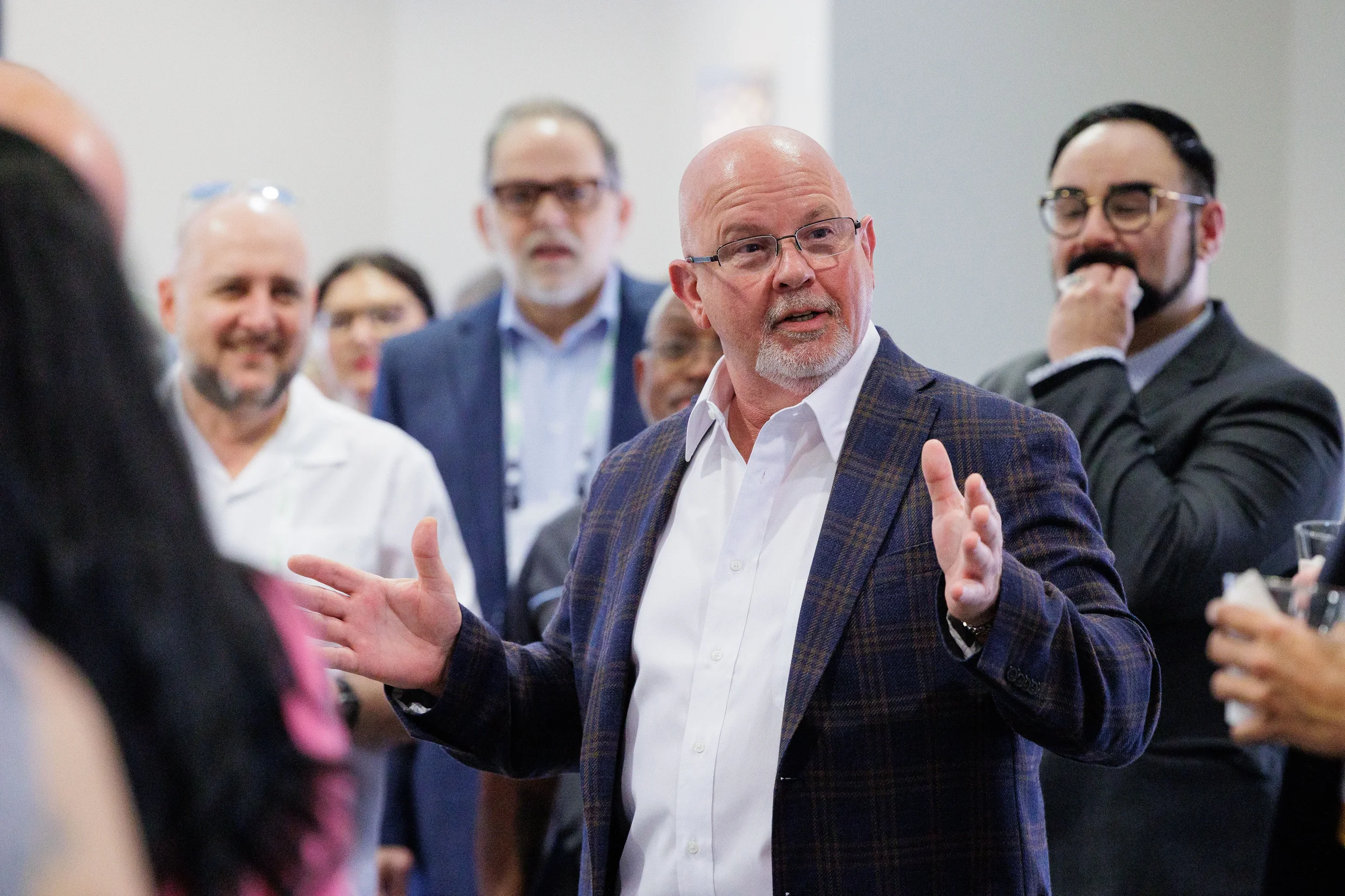 Suited speaker gestures with both hands while addressing attentive crowd at Orlando corporate conference