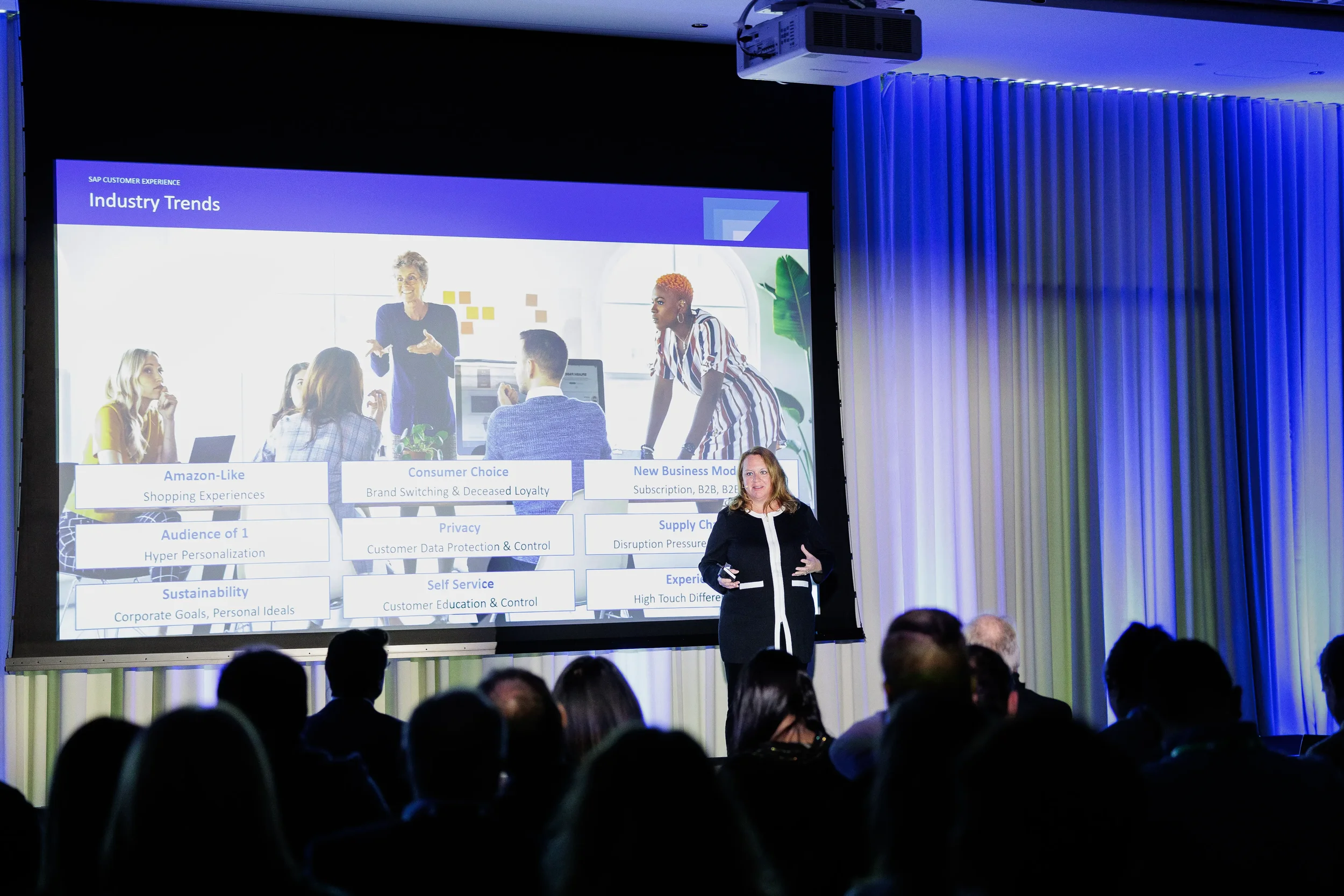 Speaker presents industry trends slide to silhouetted audience on stage at Orlando industry conference