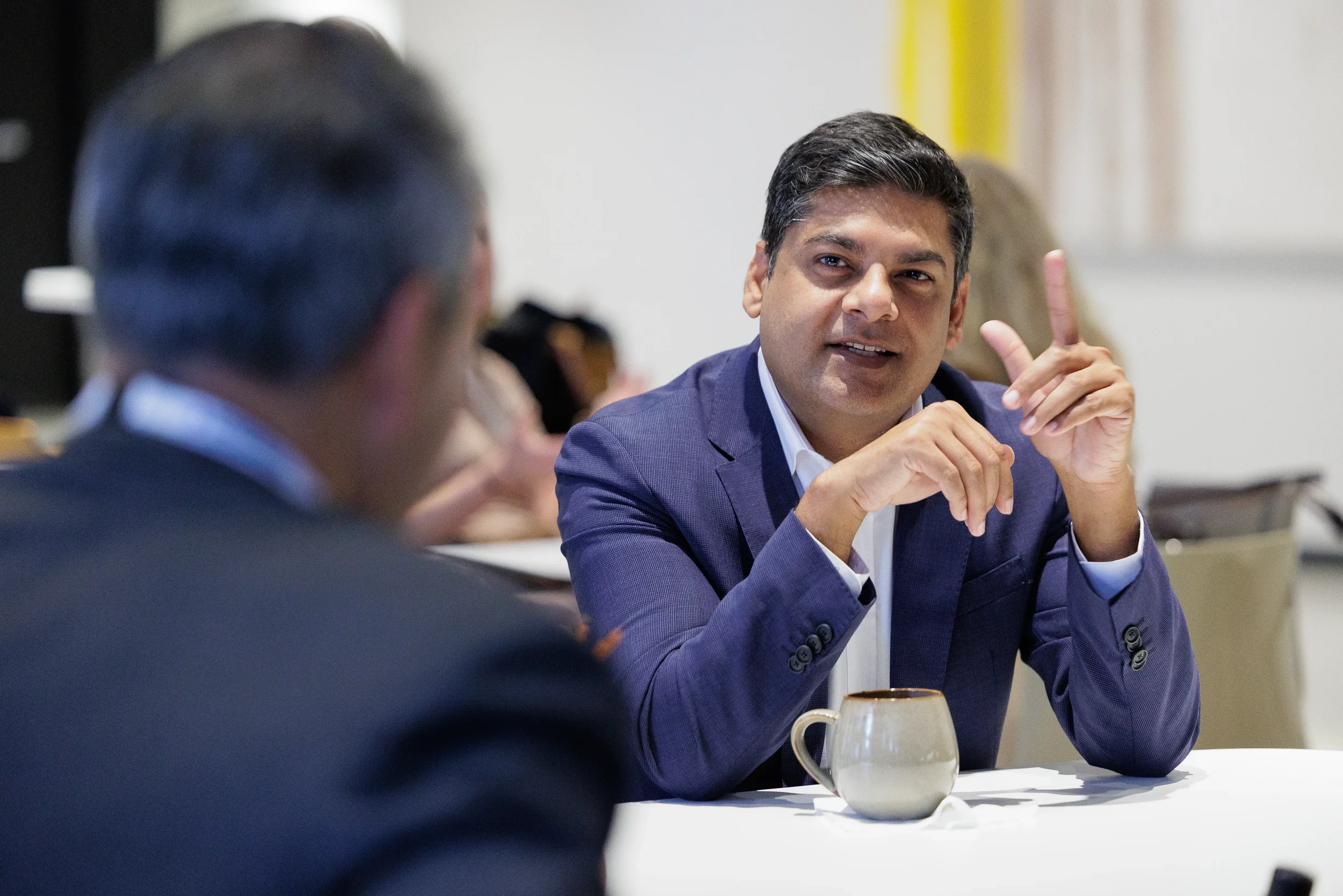 Attendee gestures while speaking during seated conversation at Chicago corporate conference