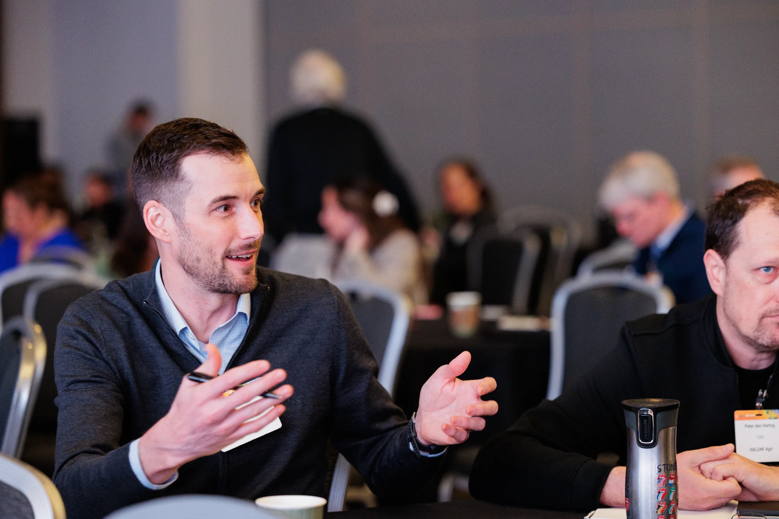 Attendee gestures while discussing topics at seated roundtable during Chicago networking event