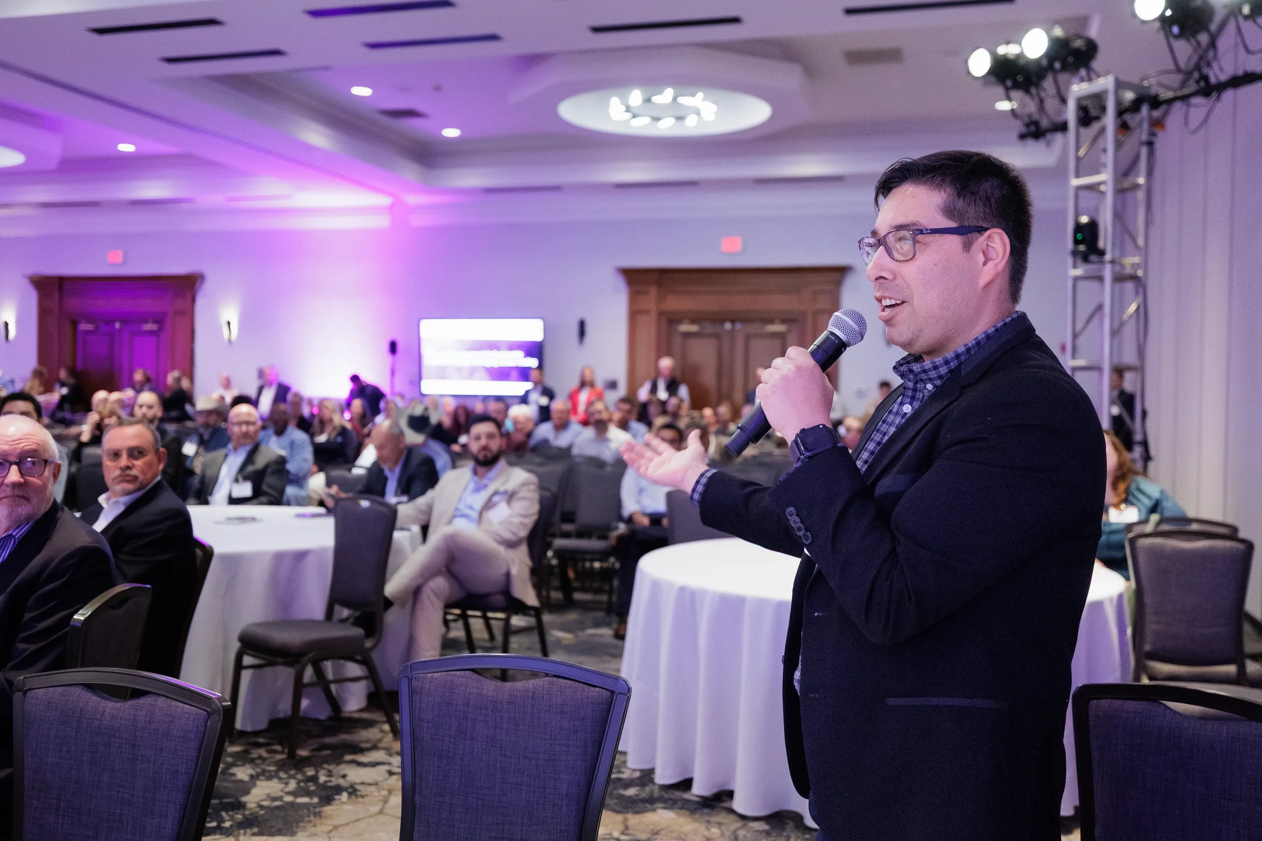 Speaker addresses seated audience while gesturing in ballroom at Chicago industry conference