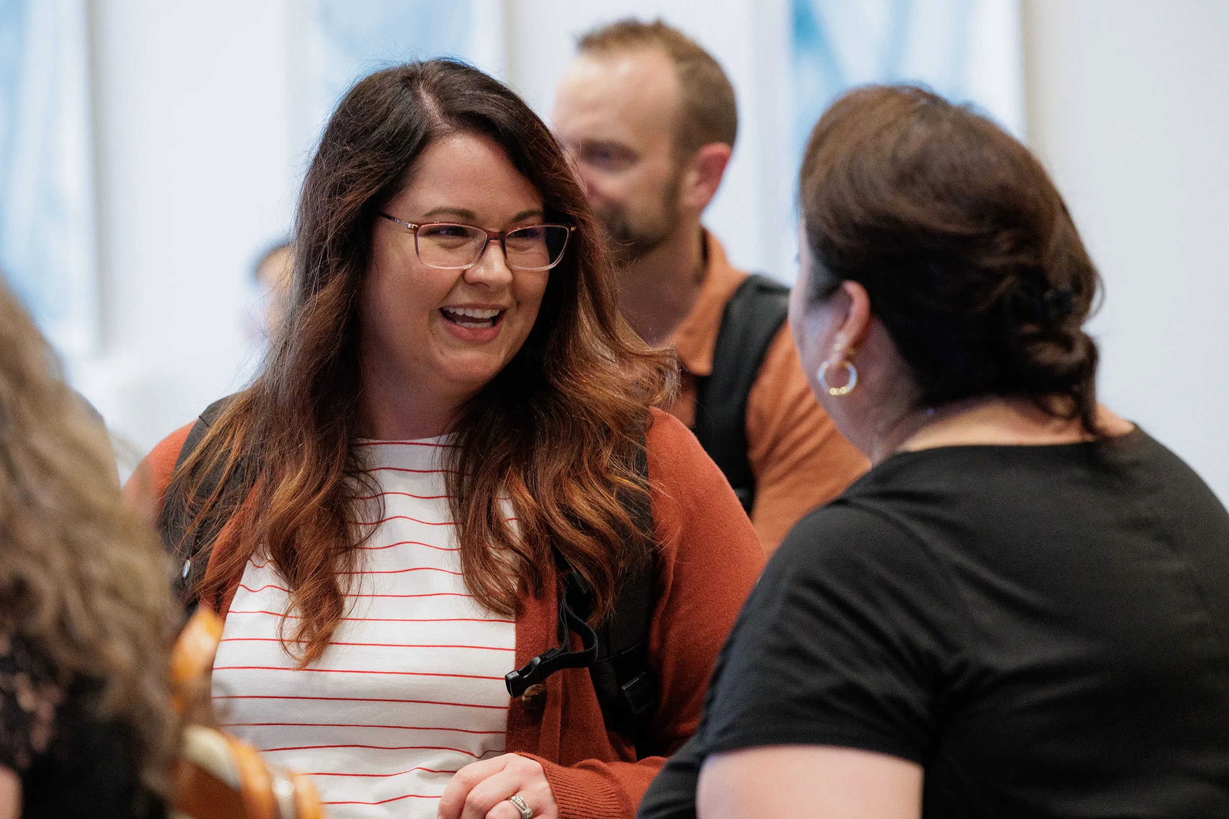 Smiling attendee with glasses laughs during networking reception at Chicago corporate conference