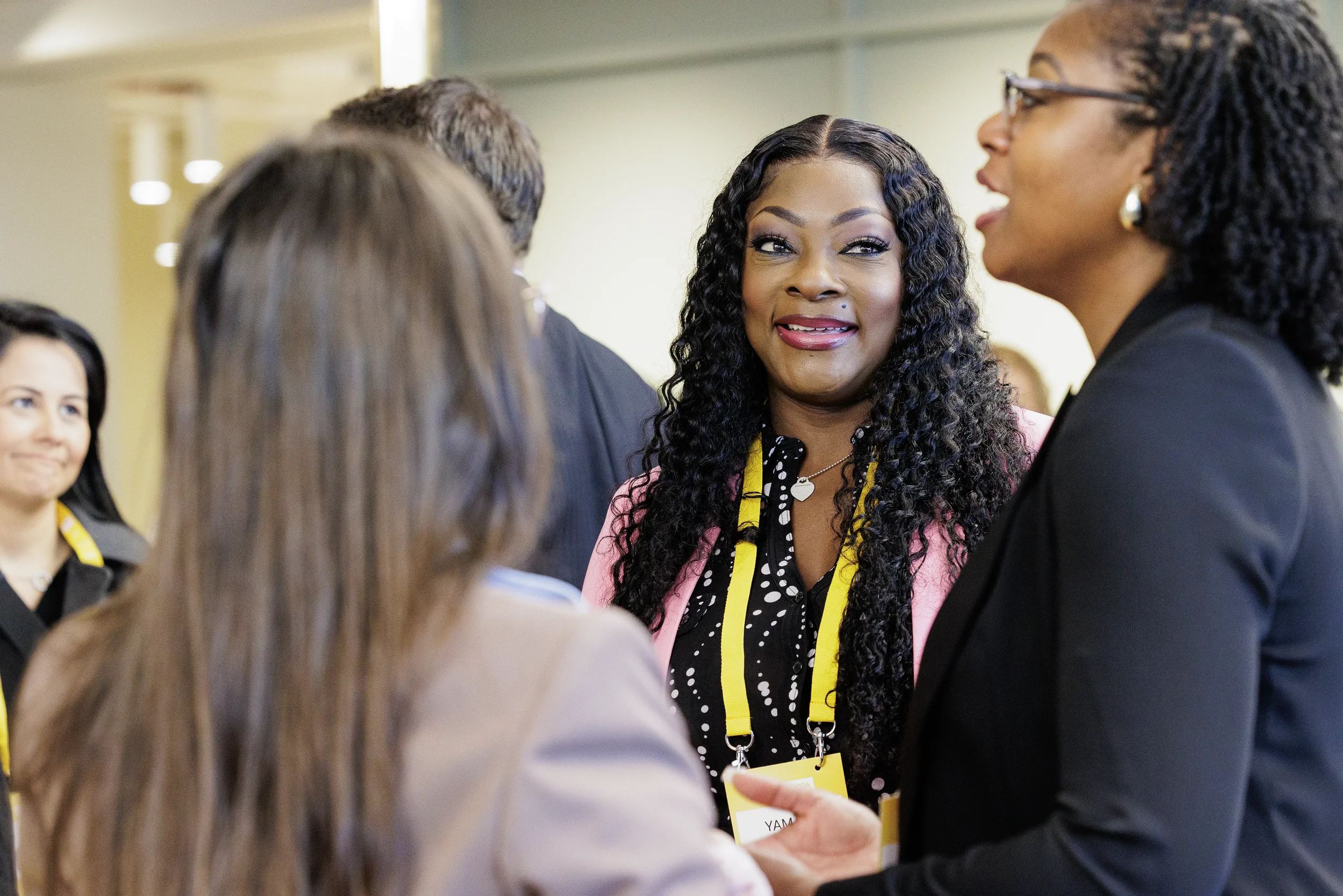 Smiling attendee with yellow lanyard joins group conversation during networking break at Chicago corporate event
