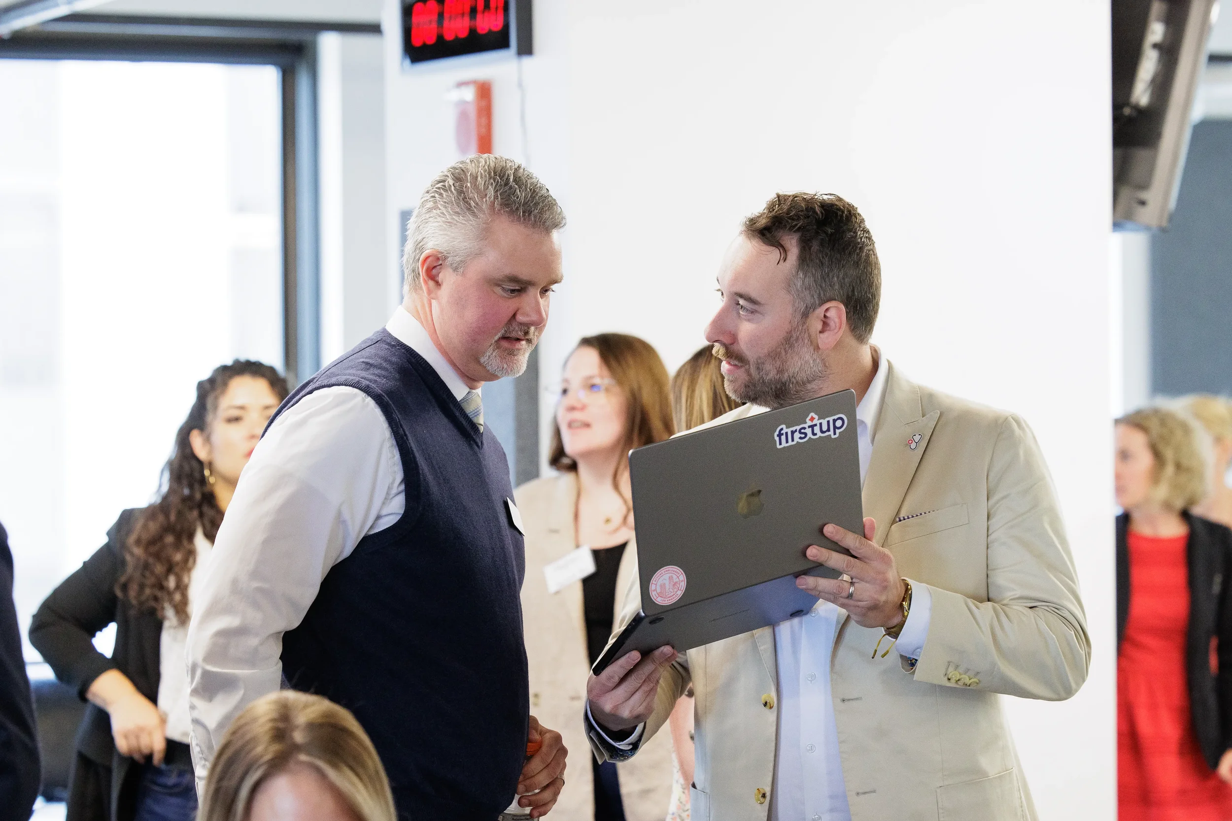 Two male attendees huddle over a laptop reviewing content during a break at Orlando corporate event