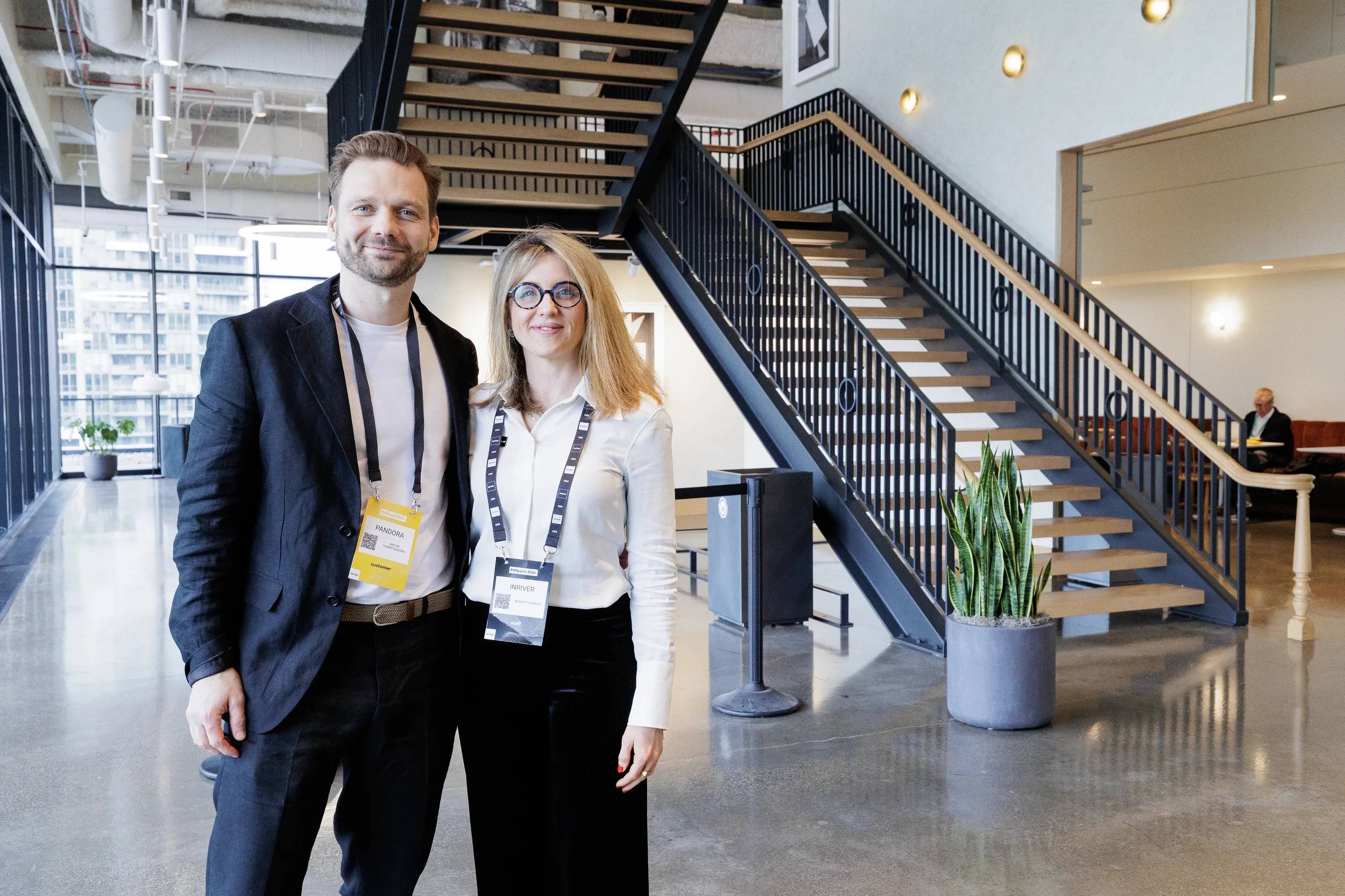 Two conference attendees with lanyards pose together near lobby staircase at Chicago corporate event