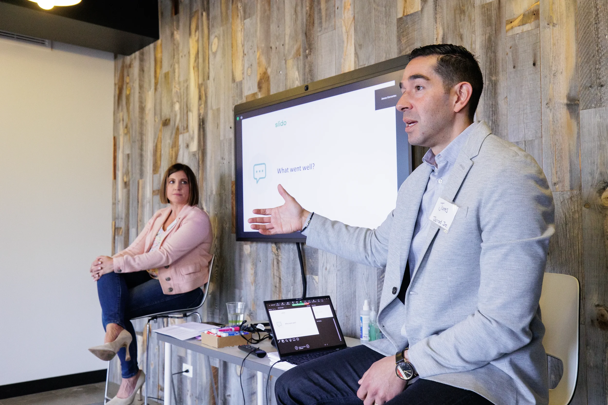 Two panelists seated before screen as male speaker gestures during Chicago industry conference