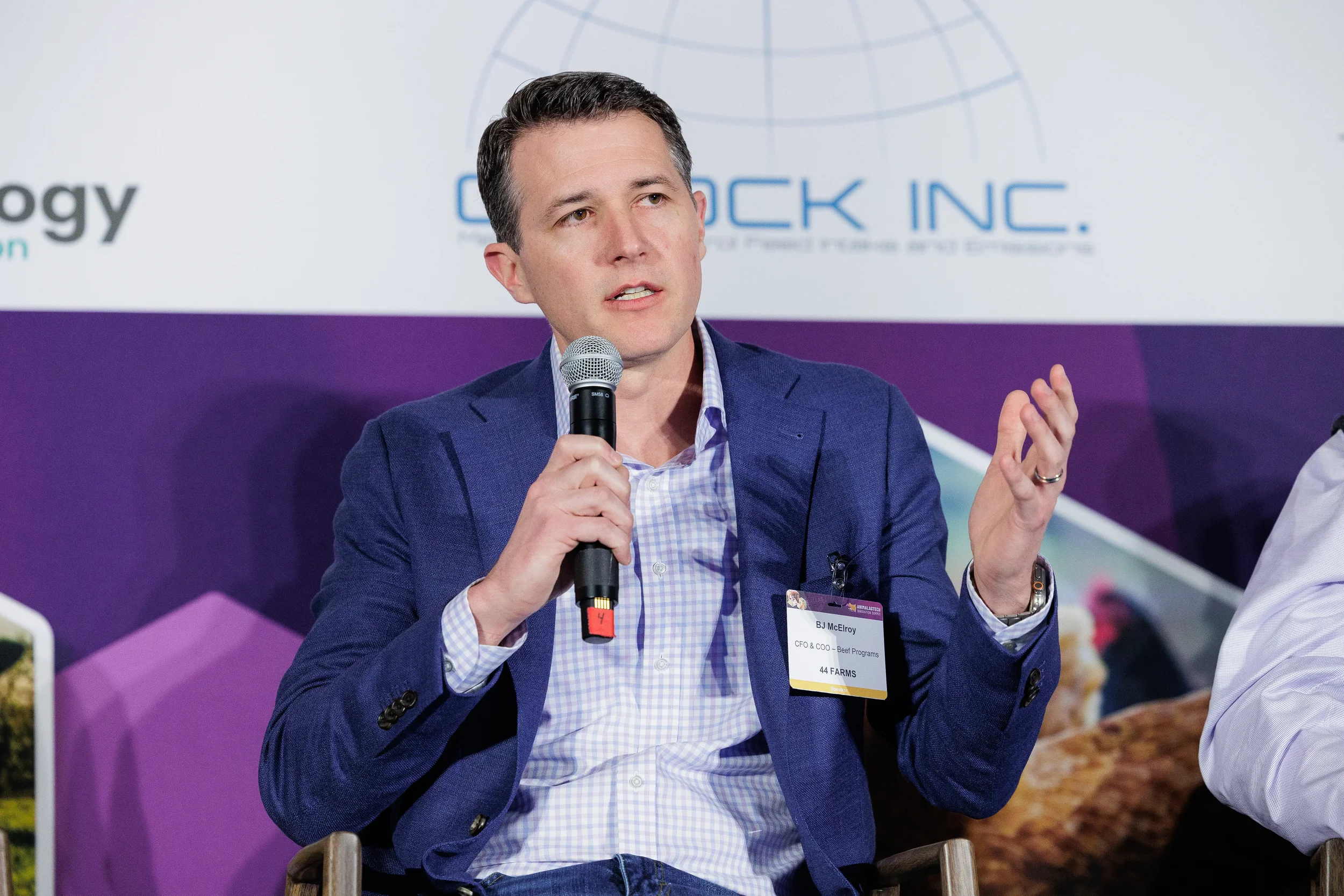 Panelist gestures while speaking into microphone during seated discussion at Chicago industry conference