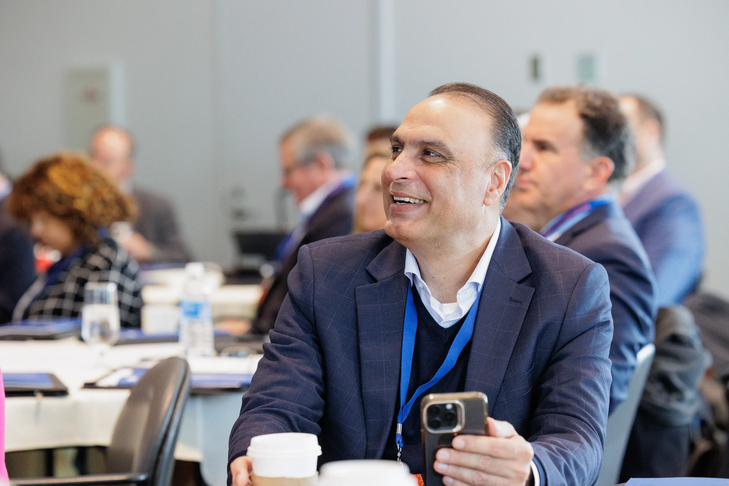 Smiling male attendee with lanyard seated at table during Orlando industry conference session