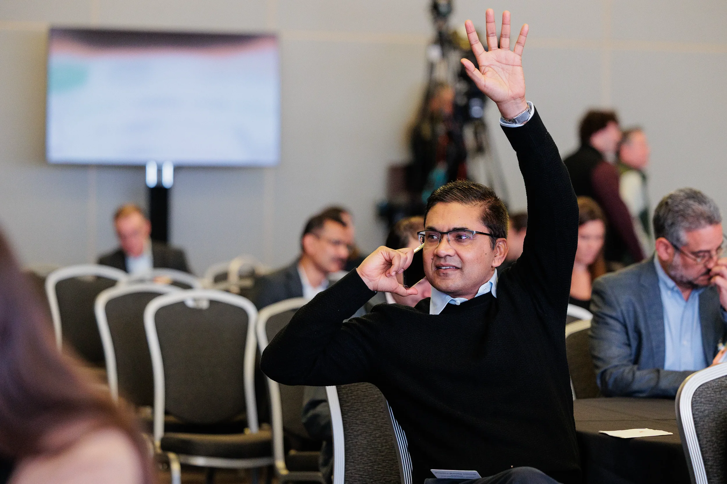 Attendee raises hand to ask question during seated session at Chicago corporate conference