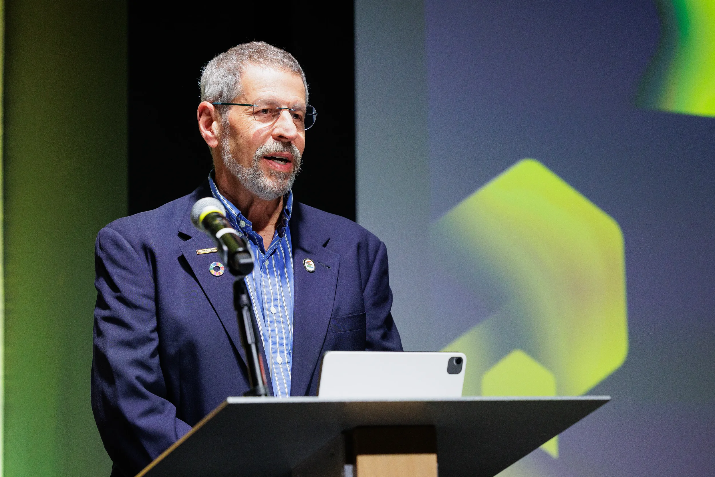 Speaker presents from podium with tablet during Chicago corporate summit session
